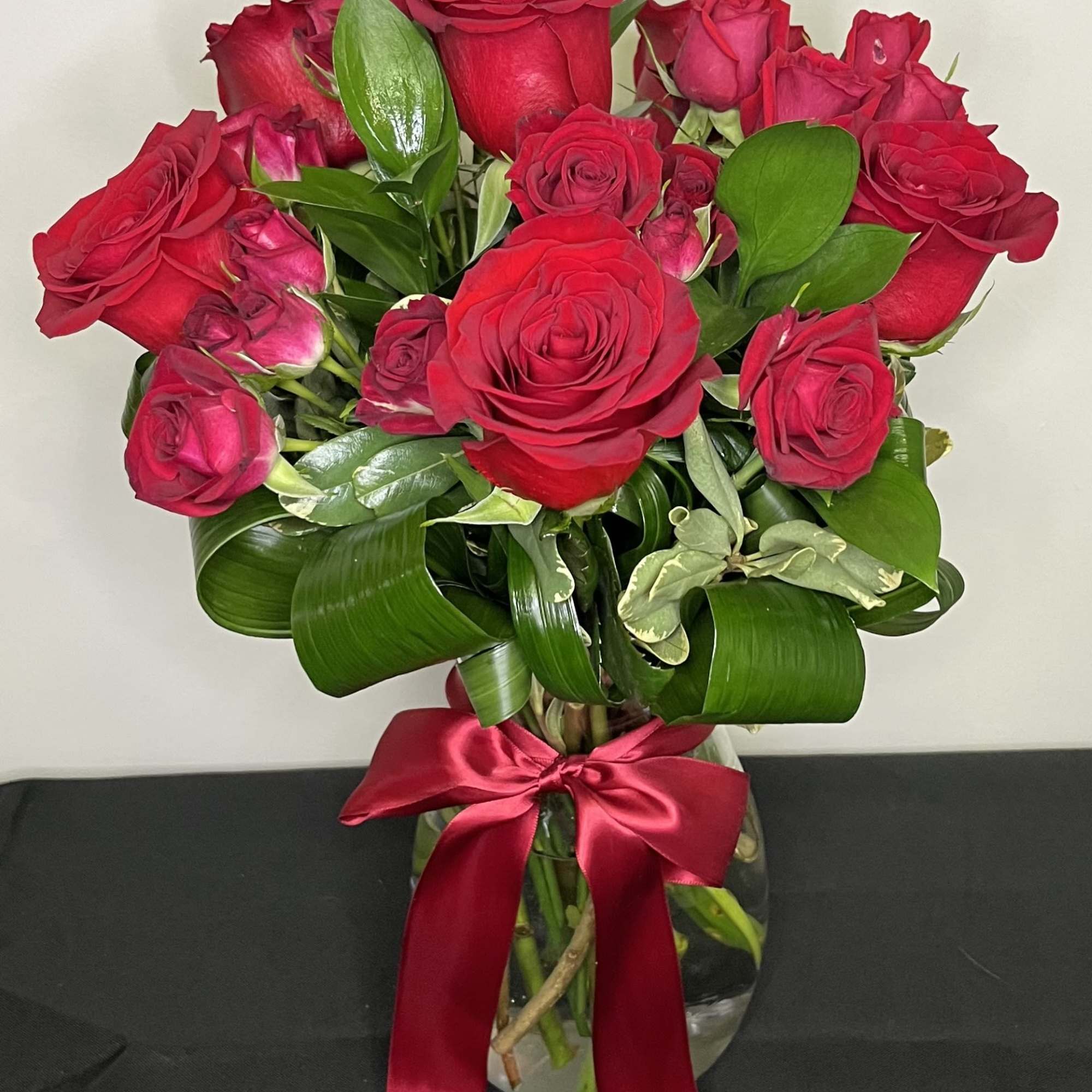 A stunning vase arrangement of rich red roses and red spray roses