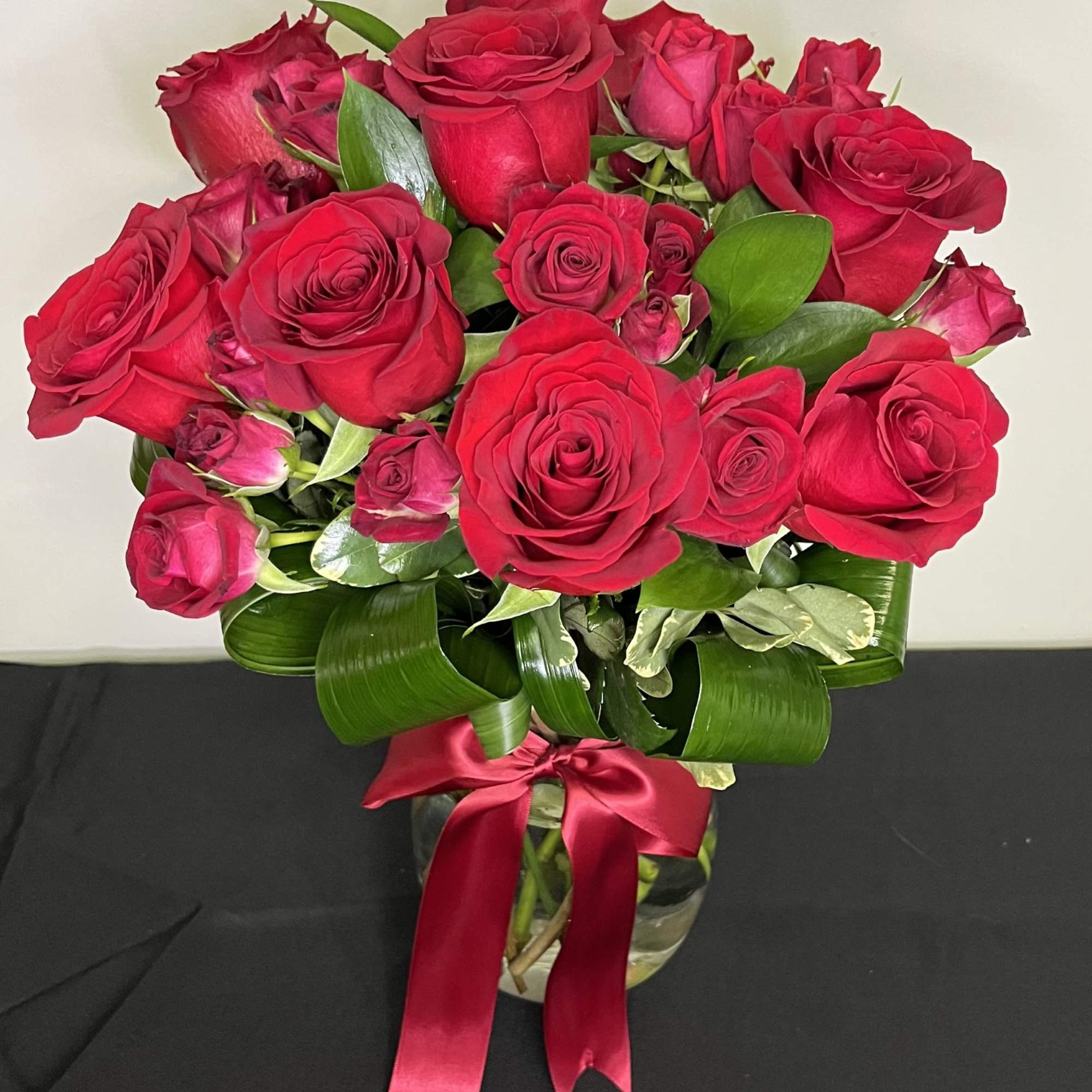 A stunning vase arrangement of rich red roses and red spray roses