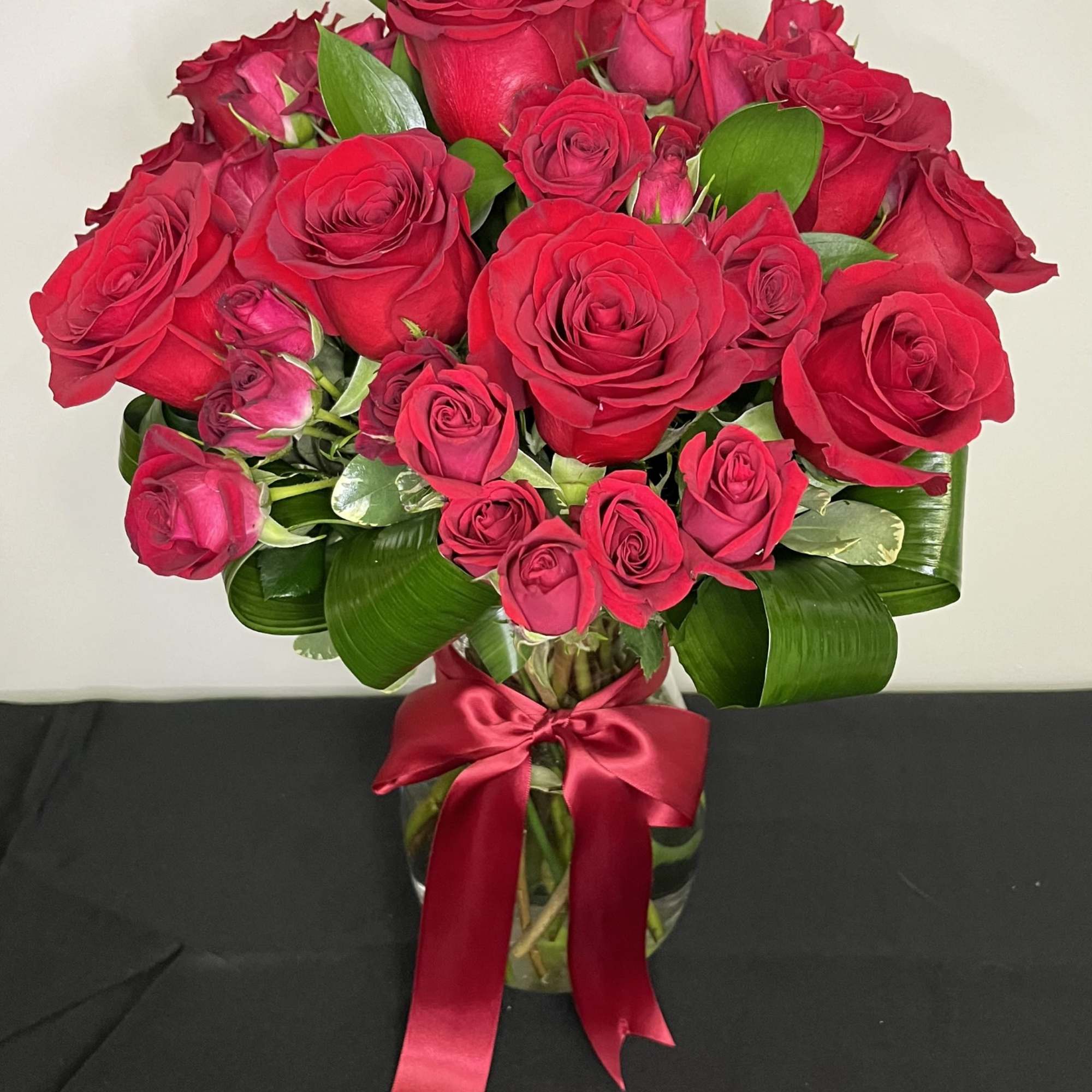 A stunning vase arrangement of rich red roses and red spray roses