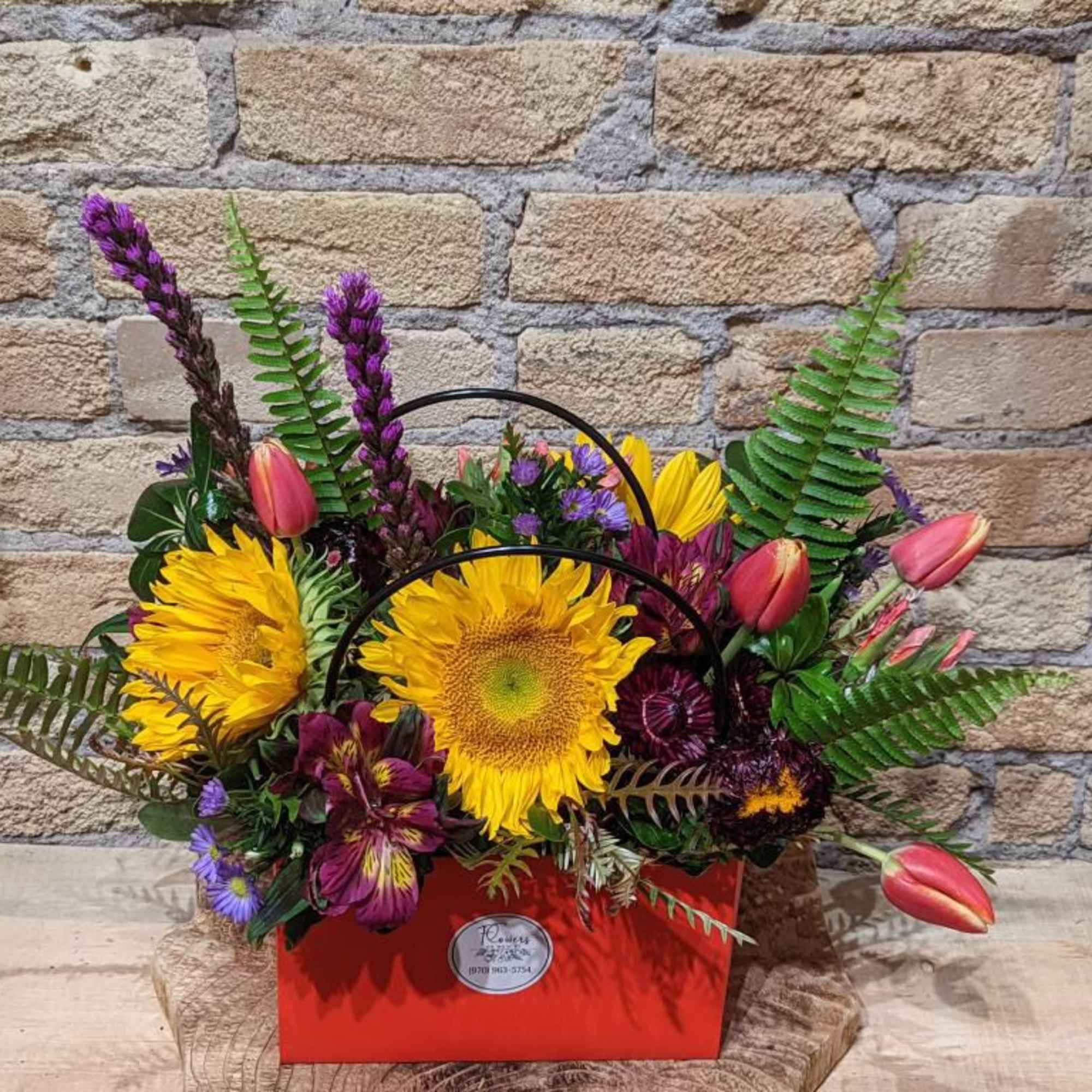 Bright mixed bouquet in a red handled box with sunflowers and tulips
