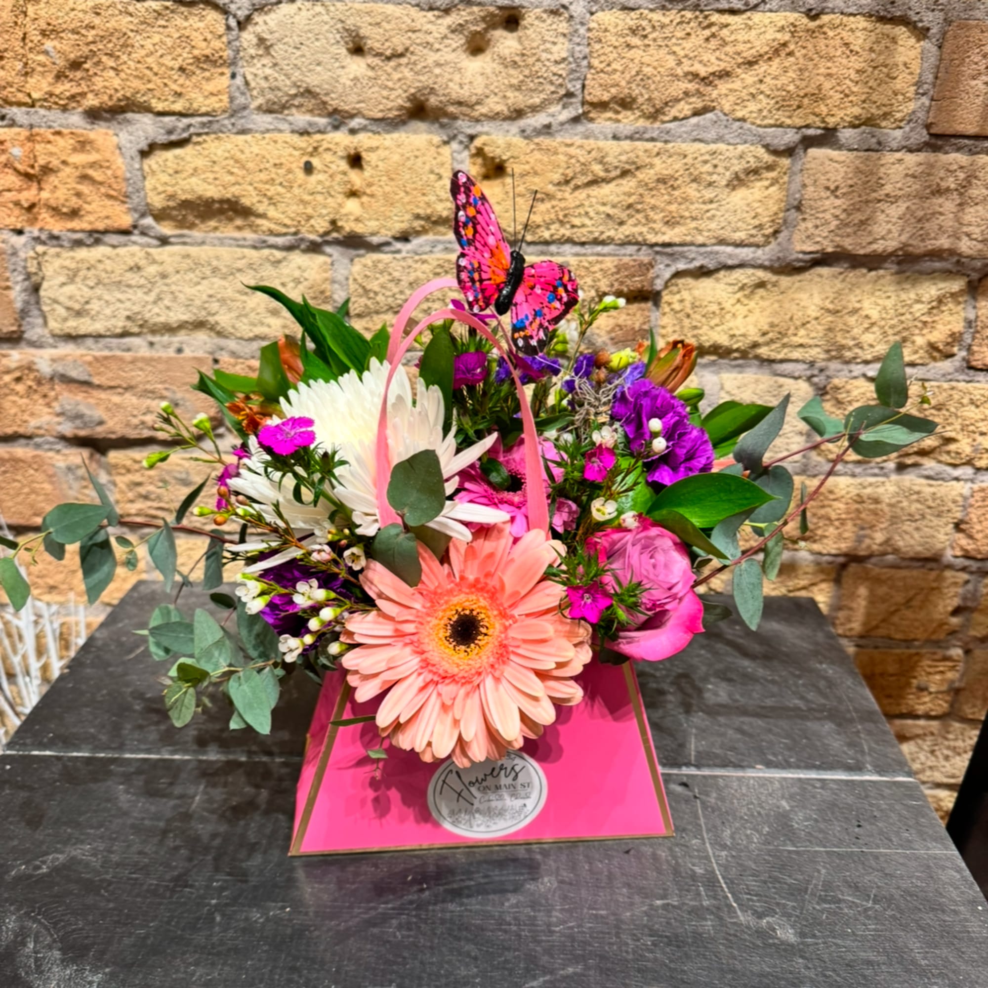 Pink and white mixed bouquet in a bright pink gift box with a butterfly topper