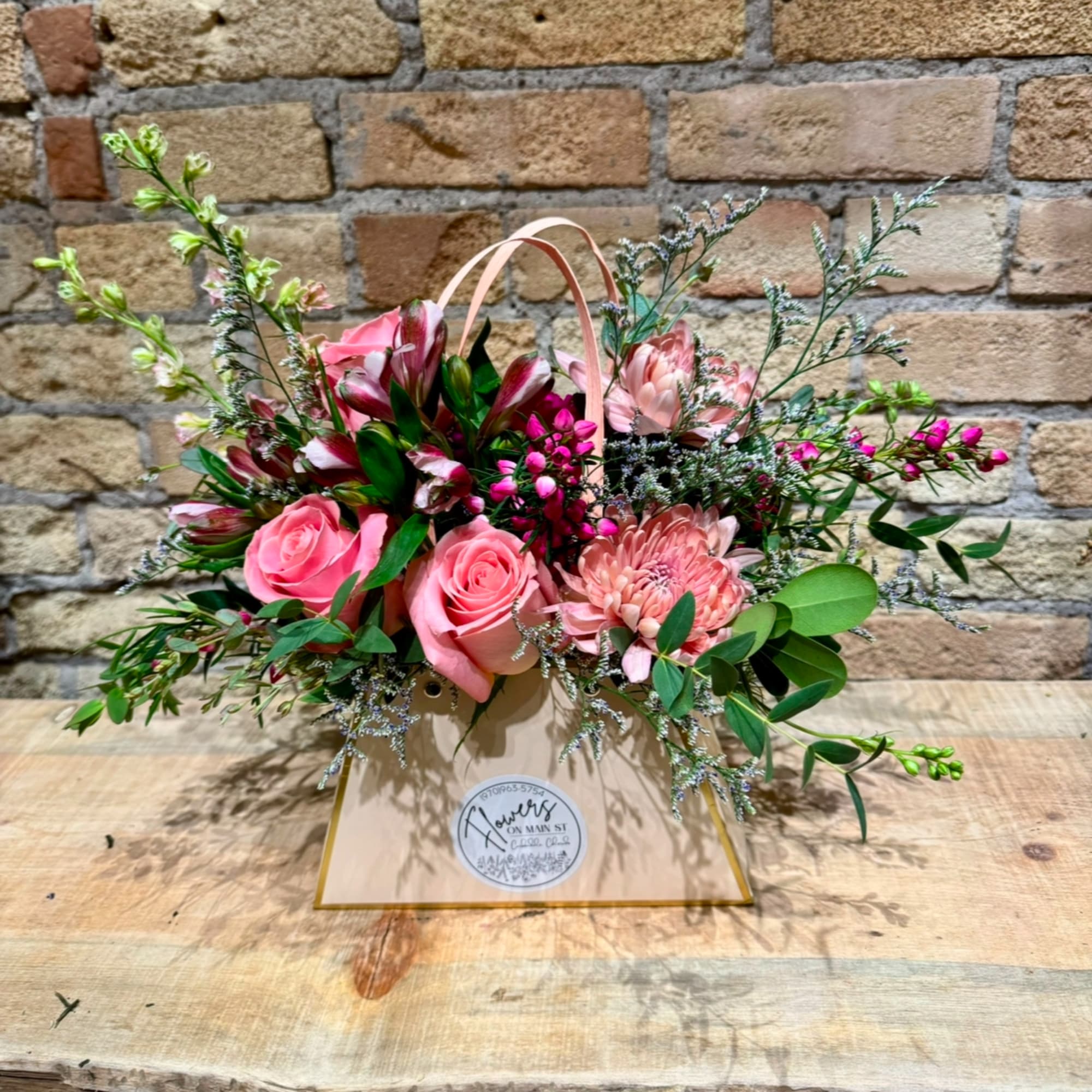 Pink roses and mixed blooms arranged in a gift bag