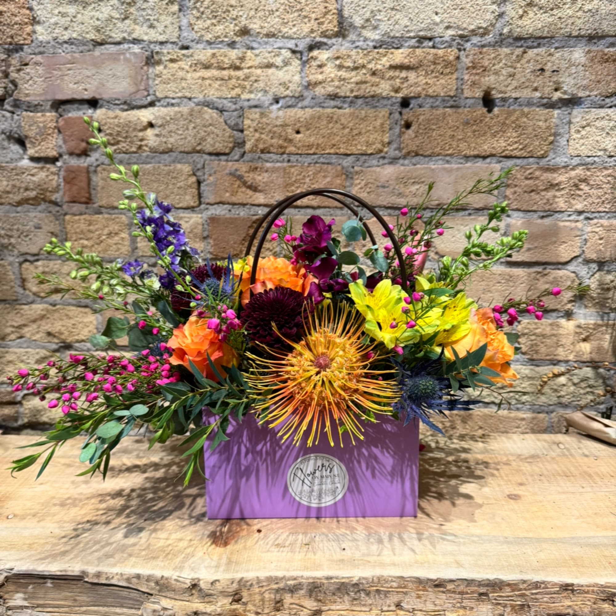 Colorful mixed flower arrangement in a purple gift box