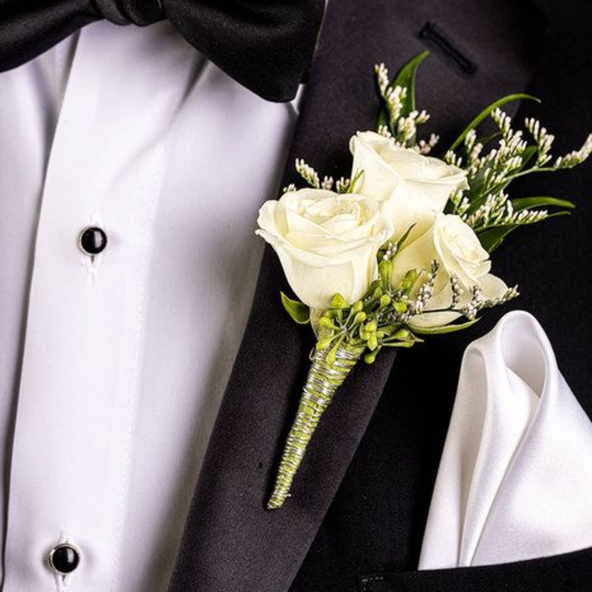 White rose boutonniere pinned to a black tuxedo jacket