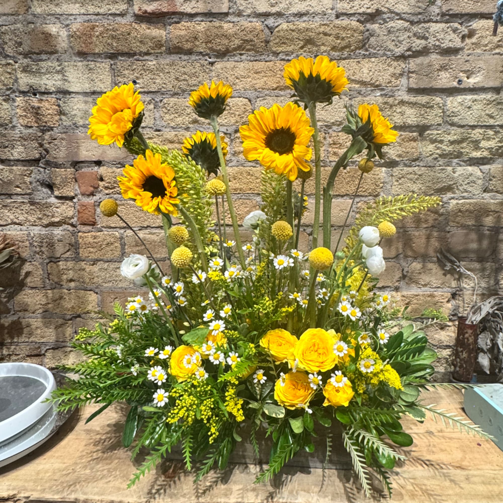 Tall yellow floral arrangement with sunflowers and small white daisies