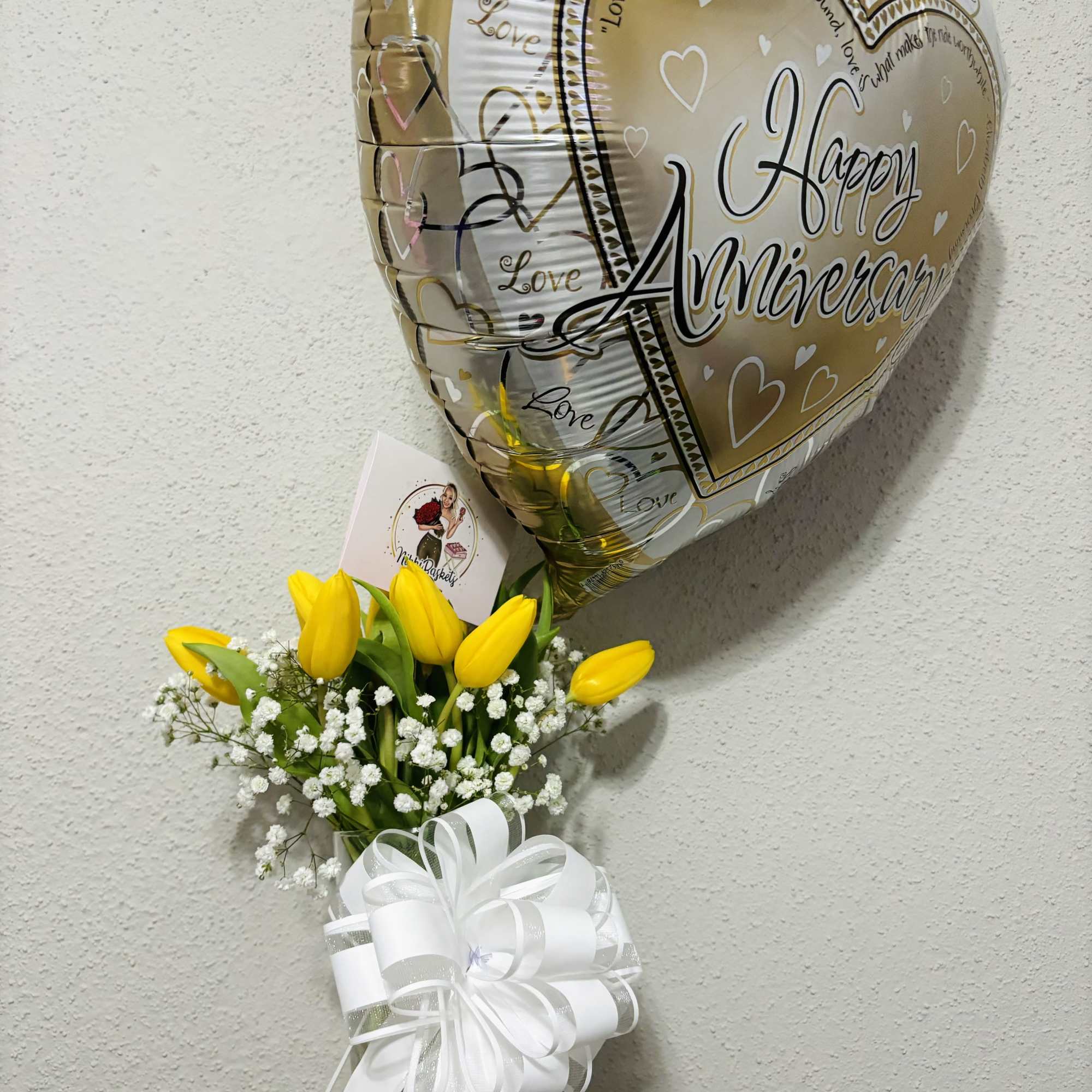 Yellow tulip bouquet in a glass vase with a gold heart balloon