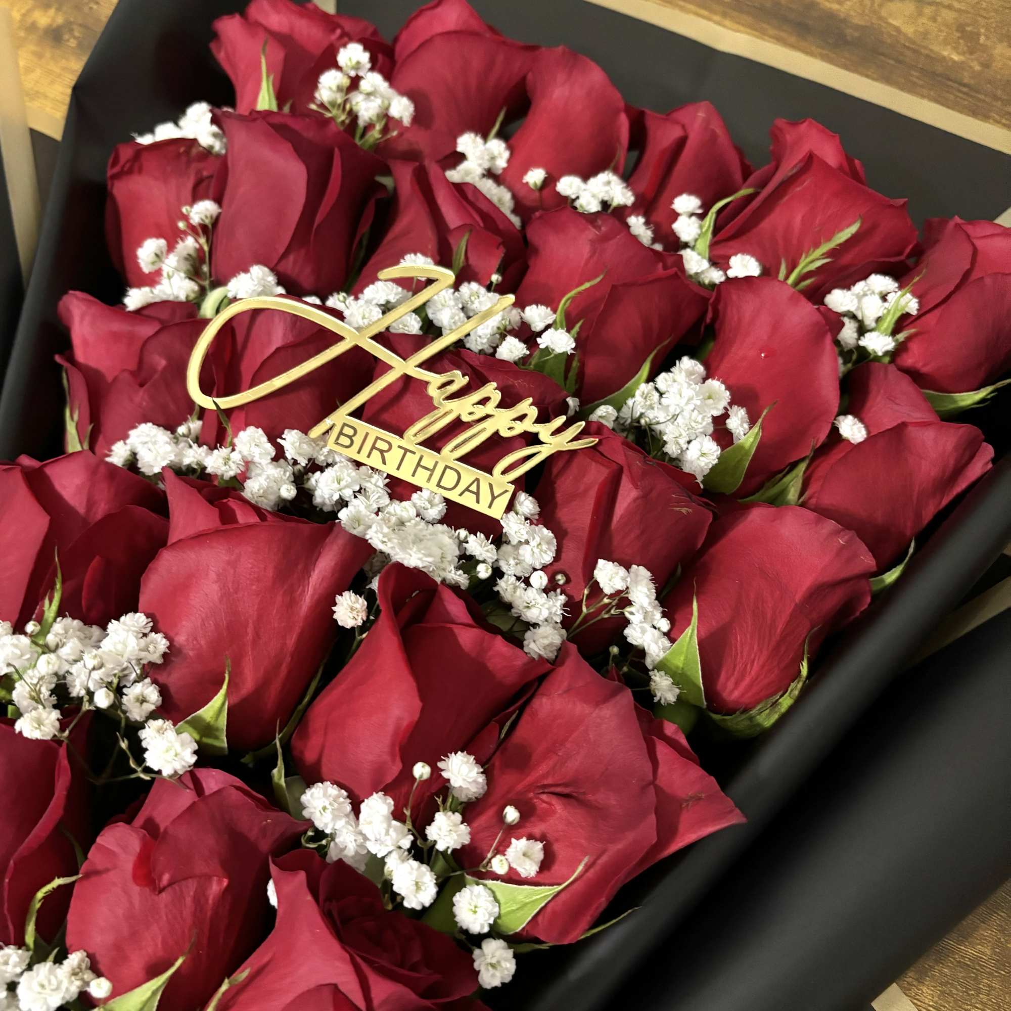 Bouquet of red roses with white baby's breath and a gold birthday topper