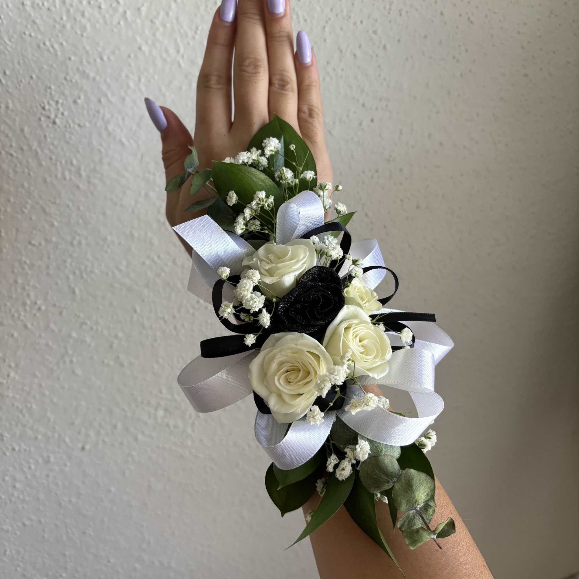 Wrist corsage with white roses, baby's breath, and black-and-white ribbons