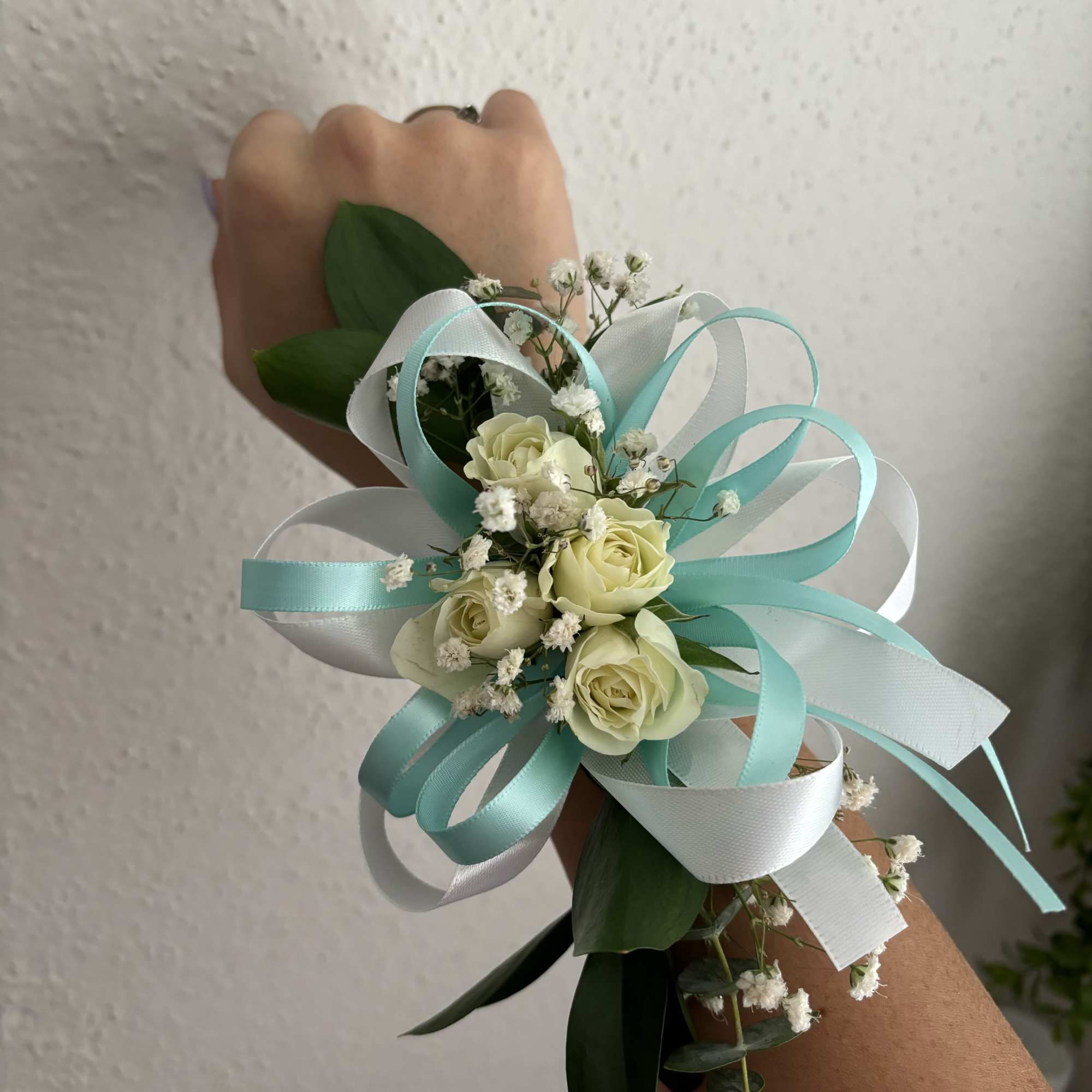 Small wrist corsage with cream roses, baby's breath, and aqua ribbons