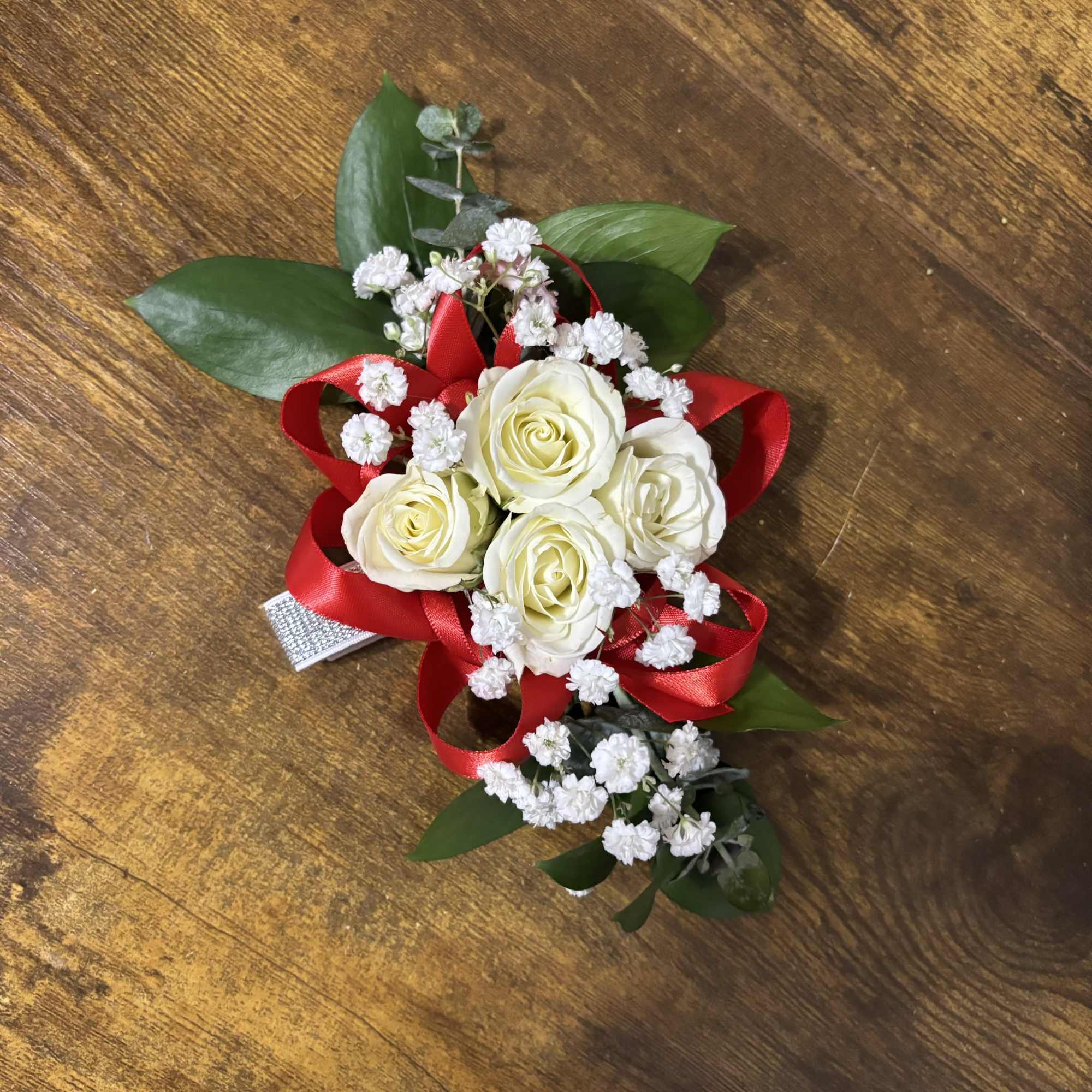 White rose corsage with red ribbon and baby's breath