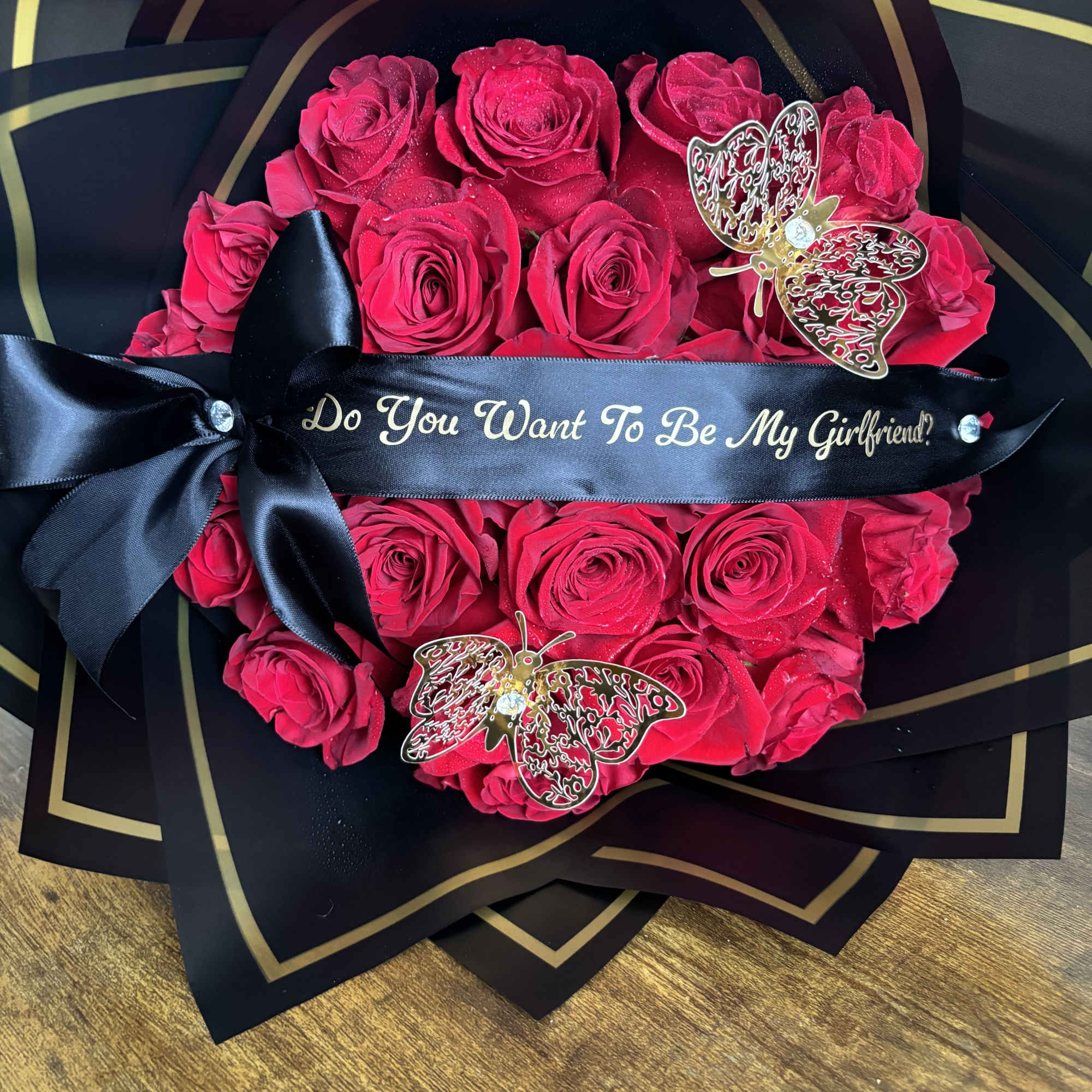 Heart-shaped bouquet of red roses with a black ribbon and butterfly accents