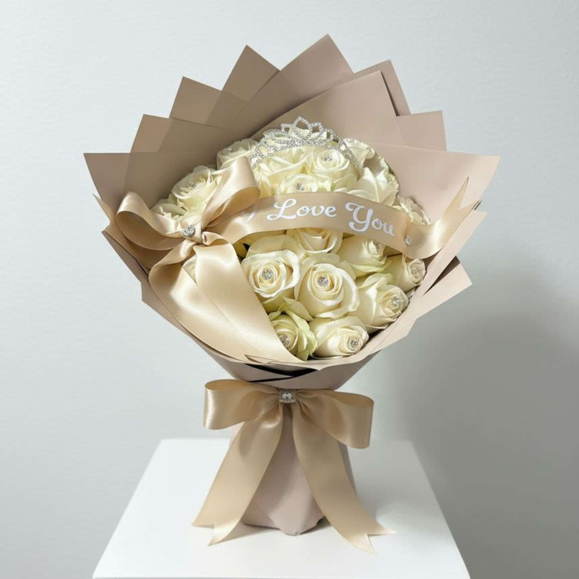 Bouquet of cream roses wrapped in beige paper with a satin bow