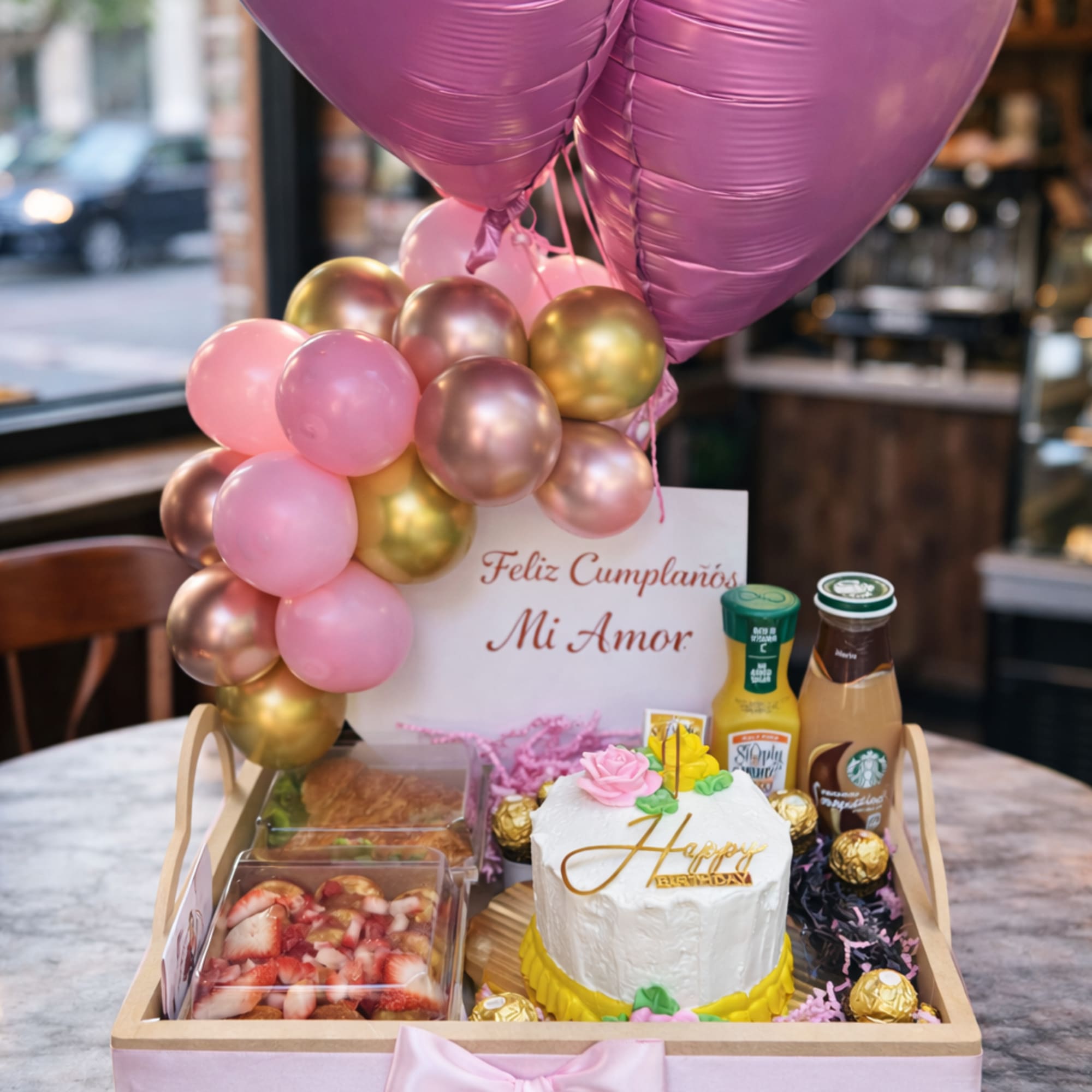 Birthday gift tray with pink heart balloons, cake, and snacks