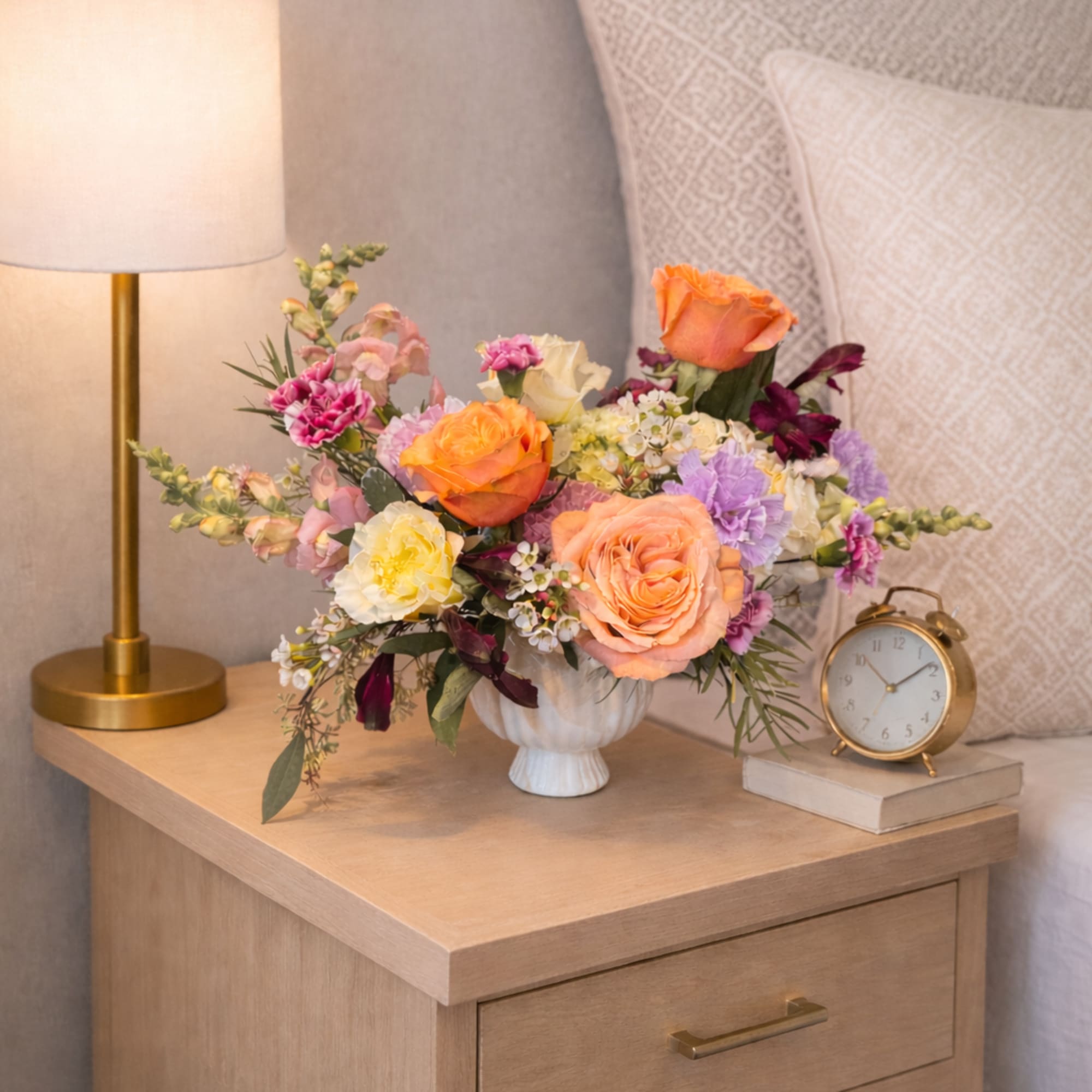 Mixed bouquet of orange, pink, and purple flowers in a white vase