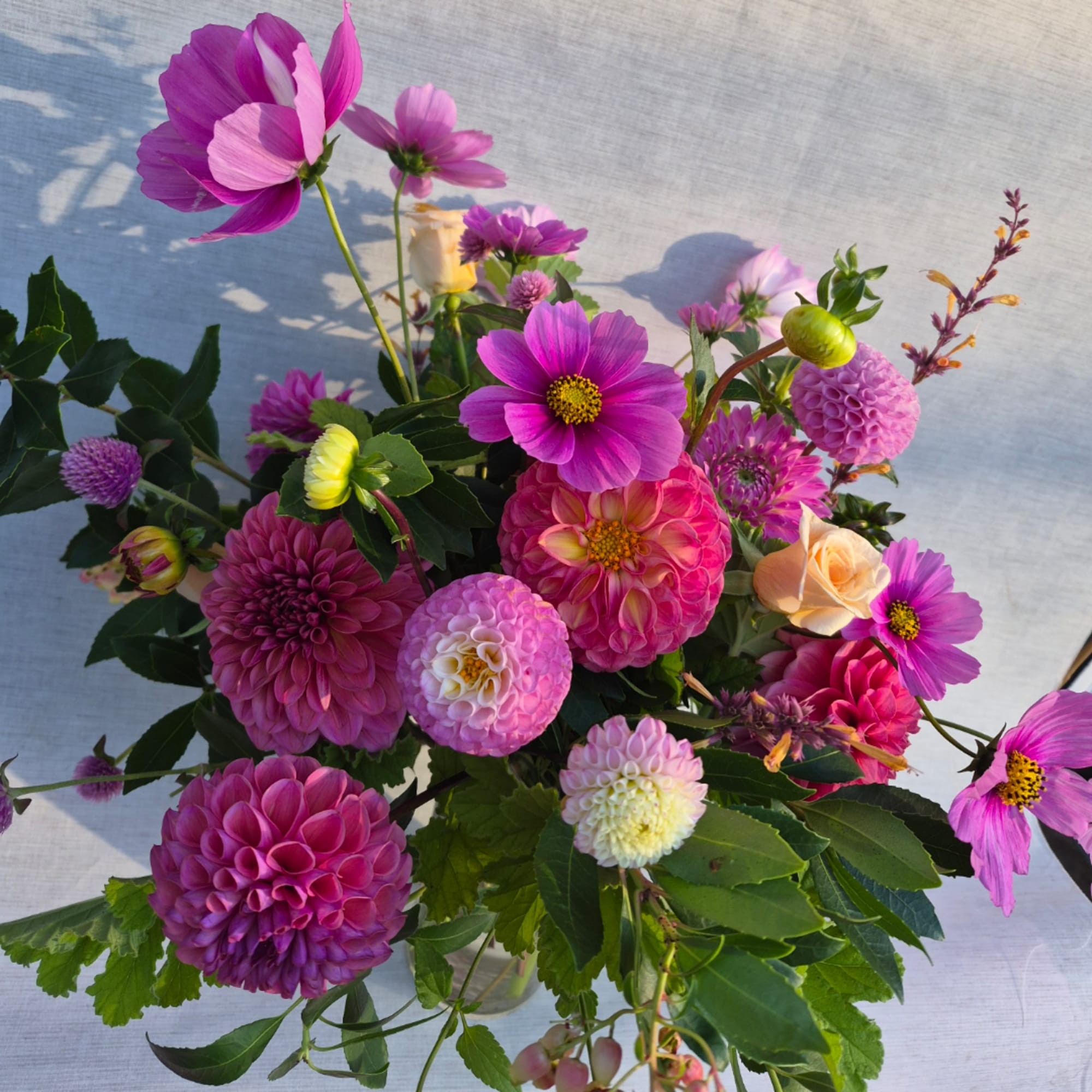 Bouquet of pink and purple flowers with a few cream roses in a clear vase