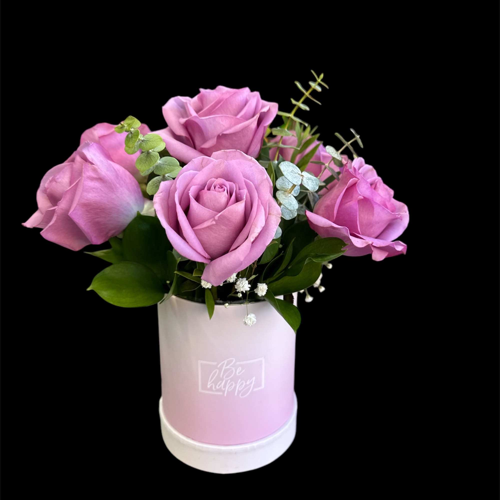 Pink roses arranged in a pastel pink box with greenery