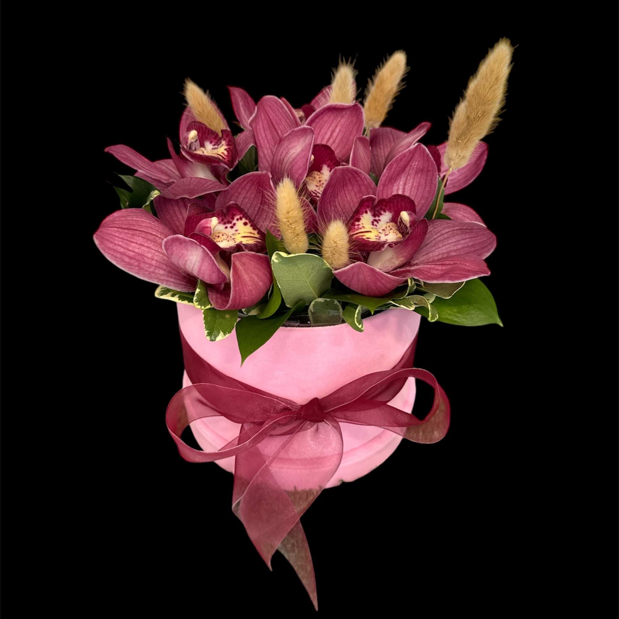Pink orchid arrangement in a pink hatbox with a ribbon bow