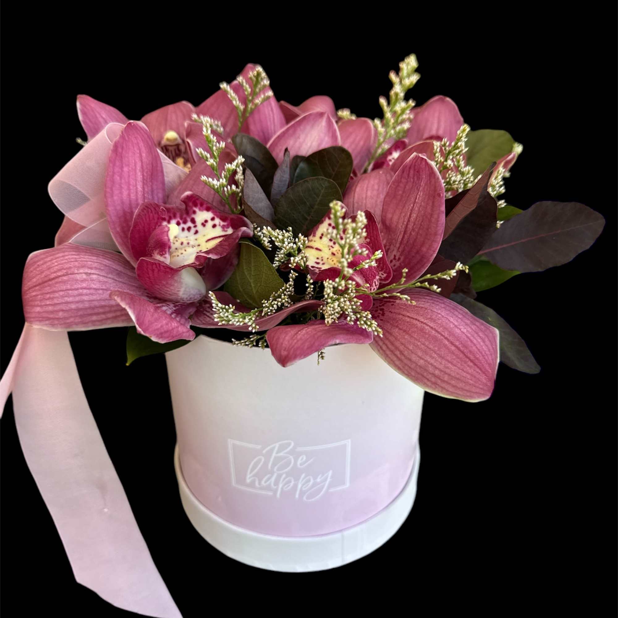 Pink orchid arrangement in a round box with a ribbon