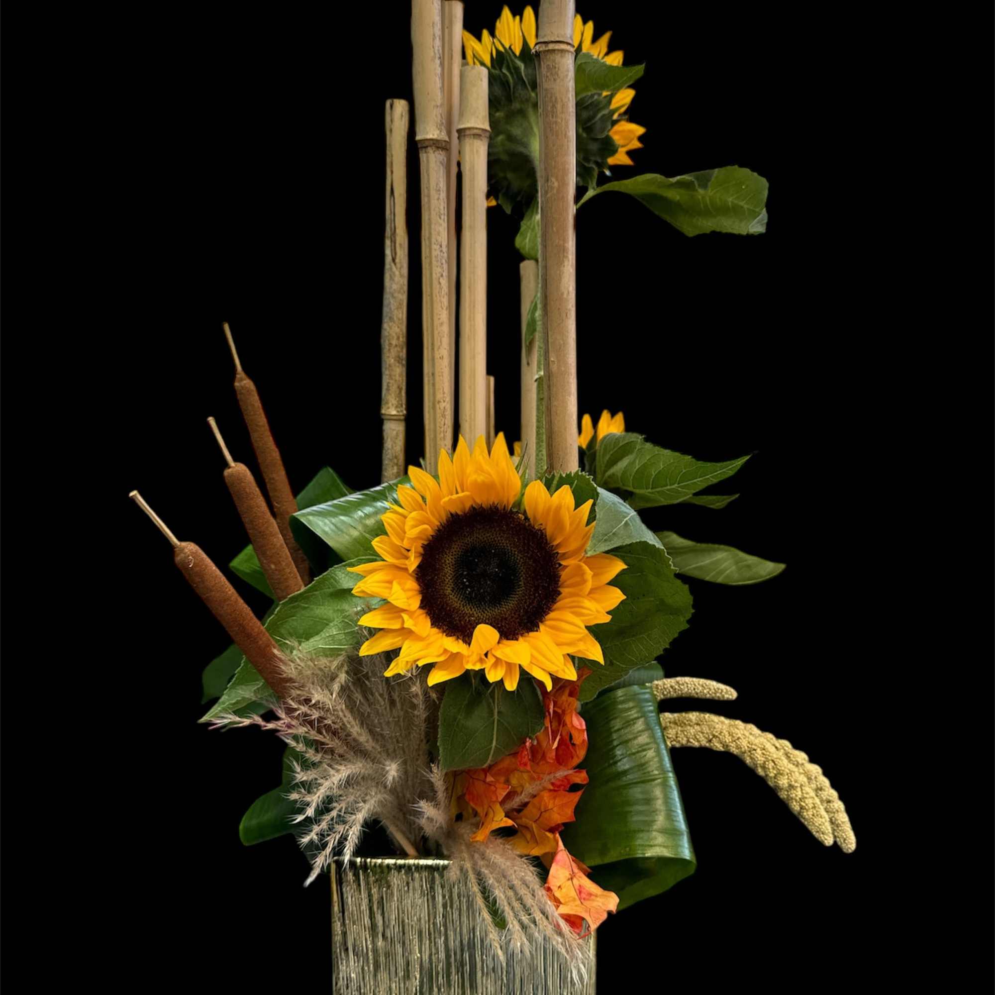 Sunflower arrangement in a square vase with cattails and bamboo accents