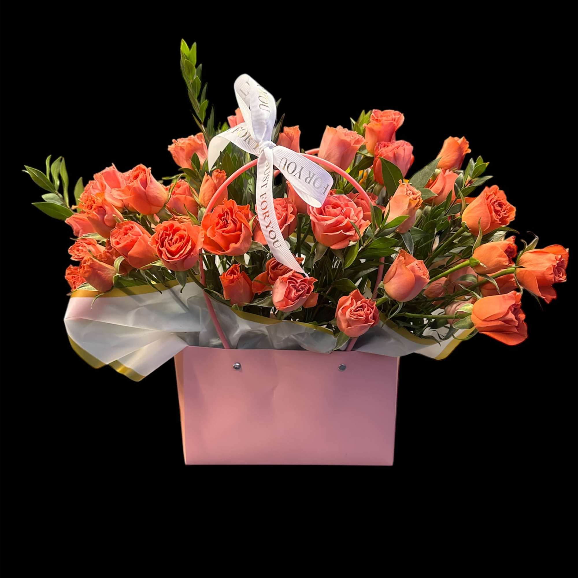 Coral roses arranged in a pink gift box with a ribbon bow