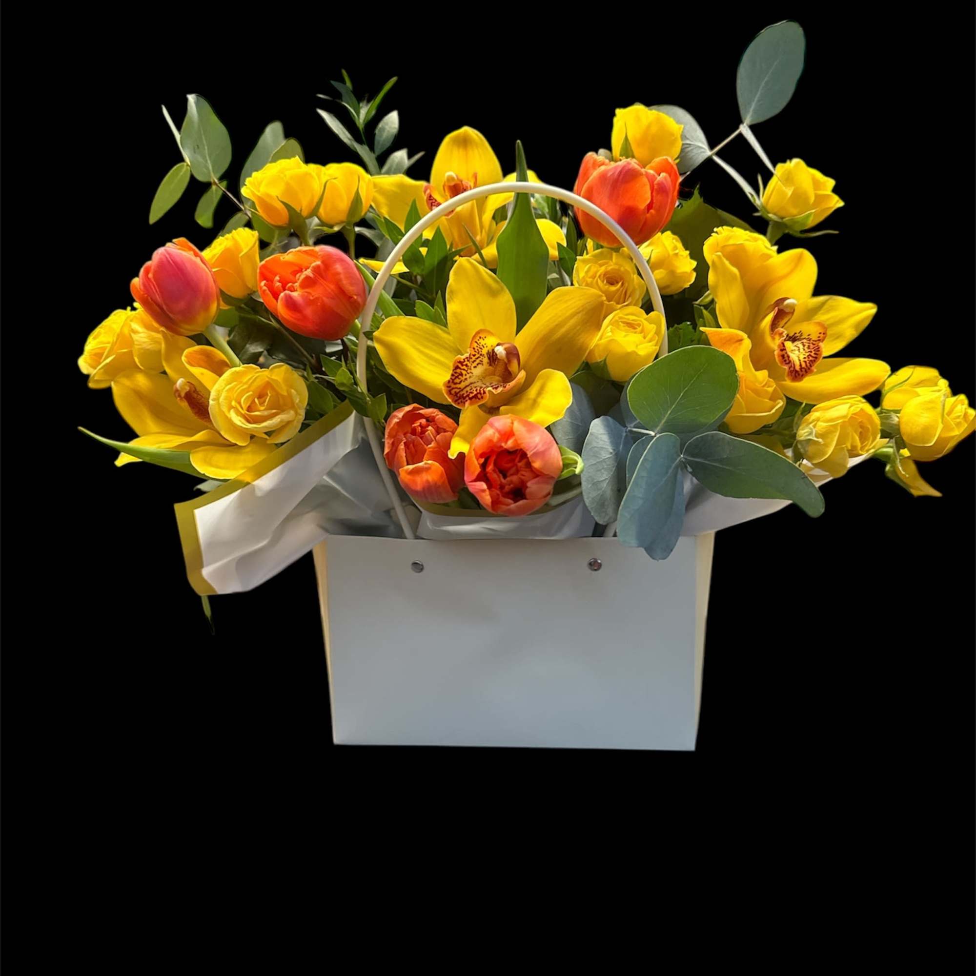 Yellow and orange tulips with orchids in a white gift bag