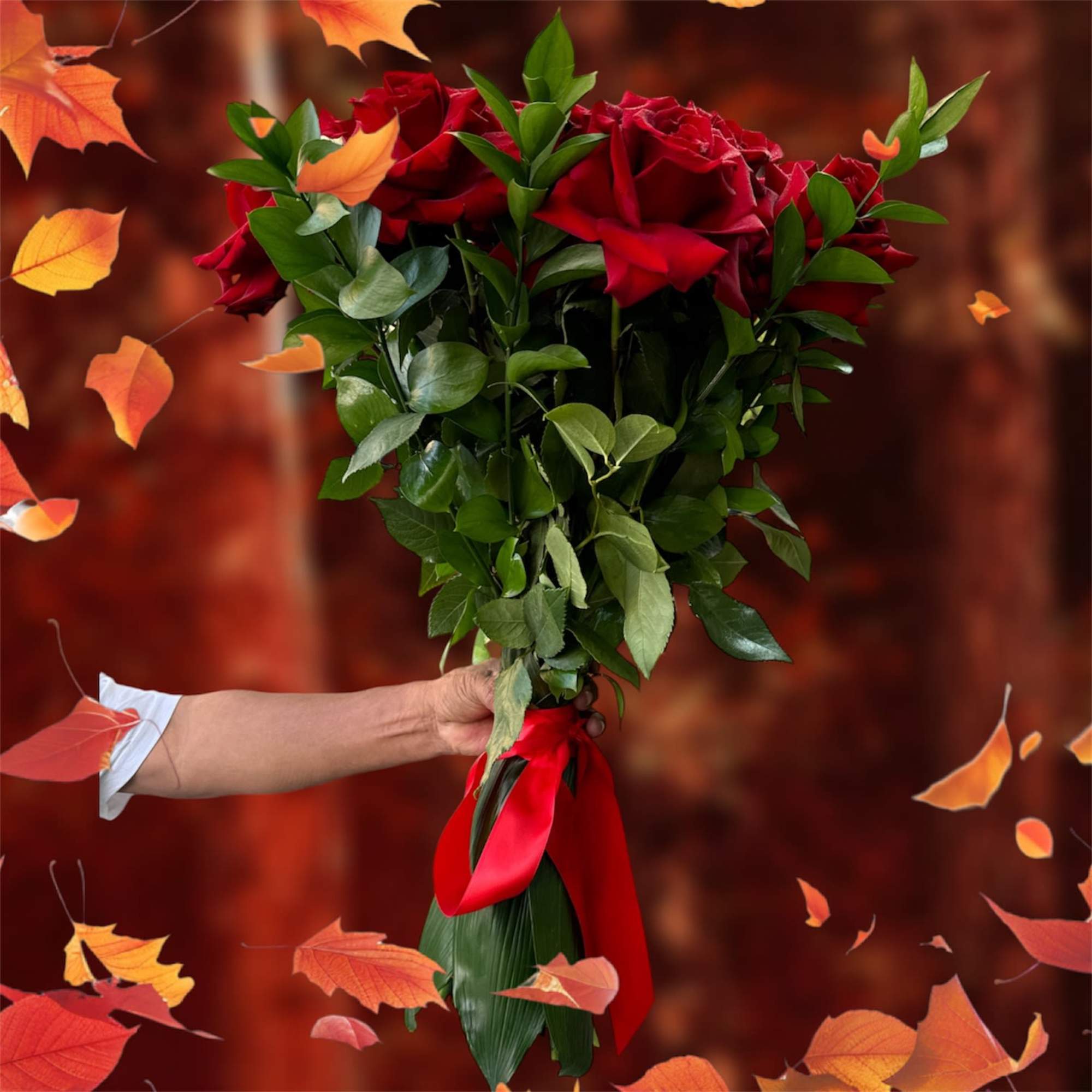 Handheld bouquet of red roses with a red ribbon