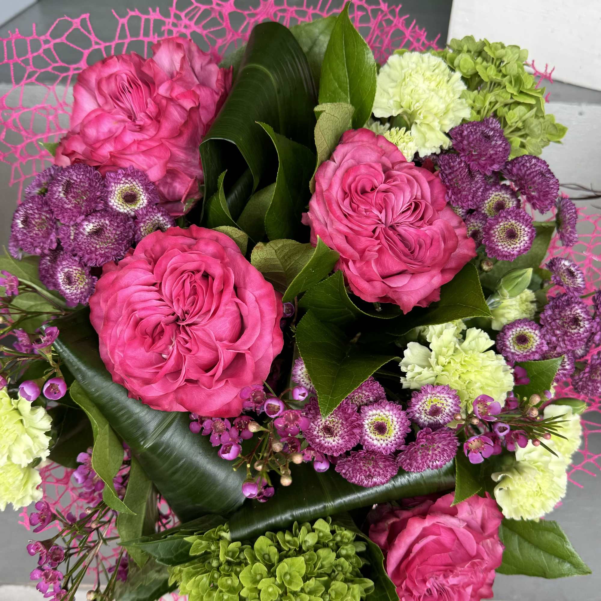 Pink roses and purple button mums with green hydrangea in a bouquet