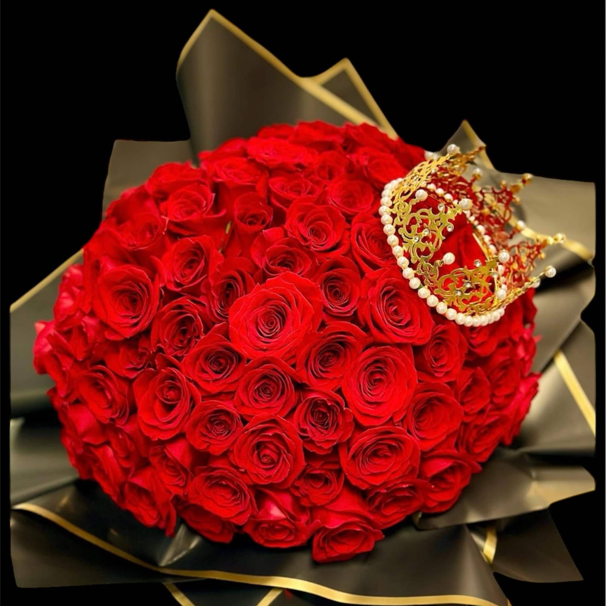 Large bouquet of red roses with a decorative crown on black wrapping