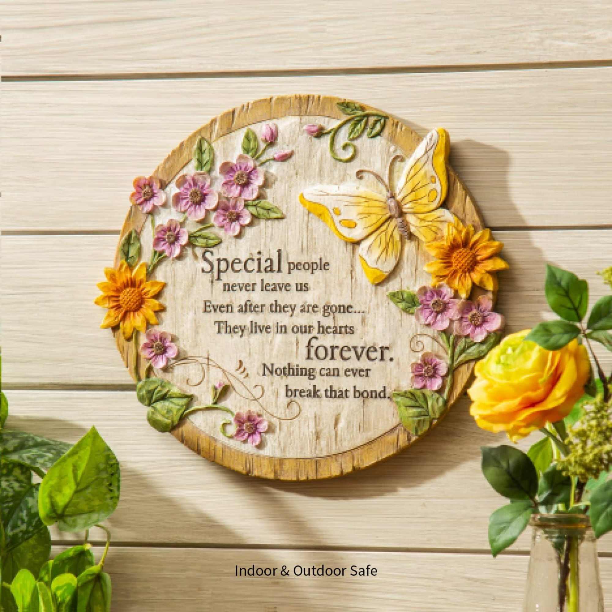 Round wooden memorial plaque with flowers and a butterfly
