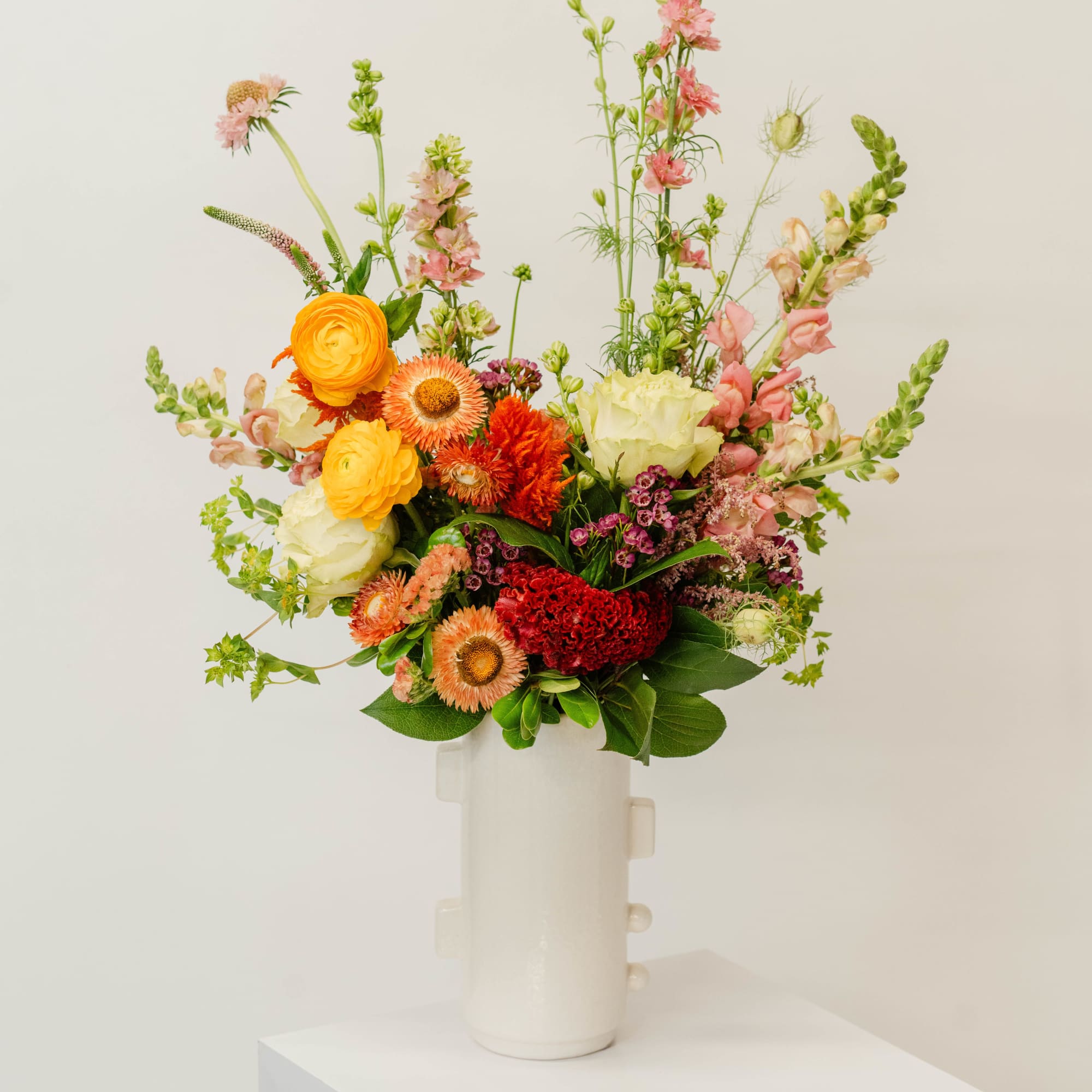 Colorful mixed bouquet in a white vase with tall pink stems