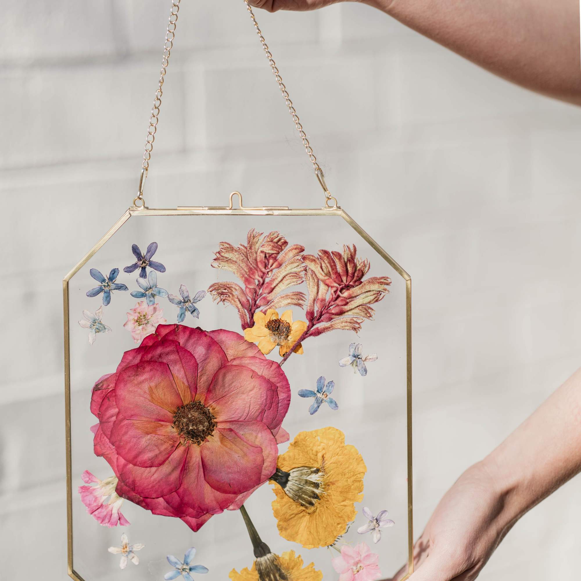 Pressed flowers in a gold-framed hanging glass panel