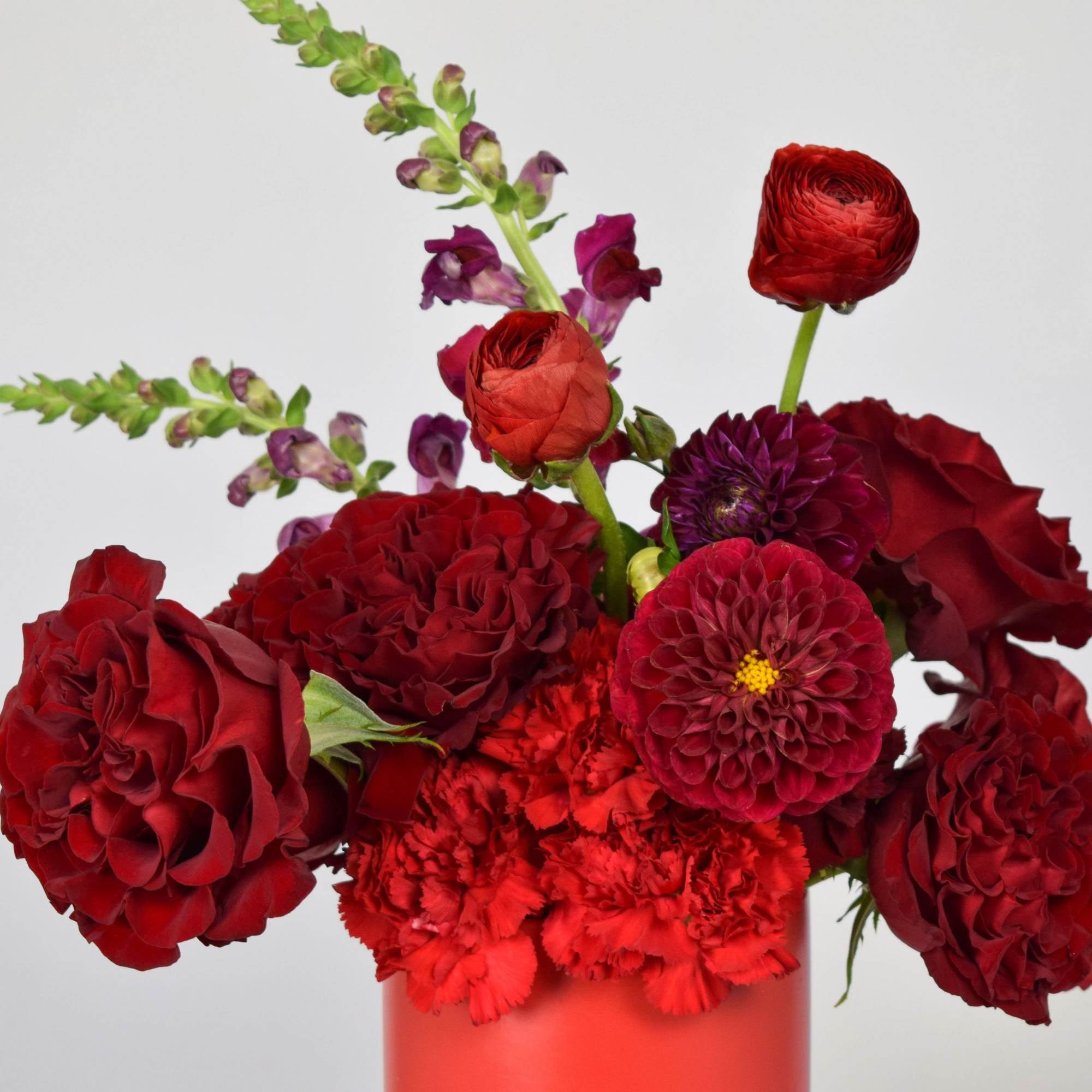 Red floral arrangement with dahlias and carnations in a vase