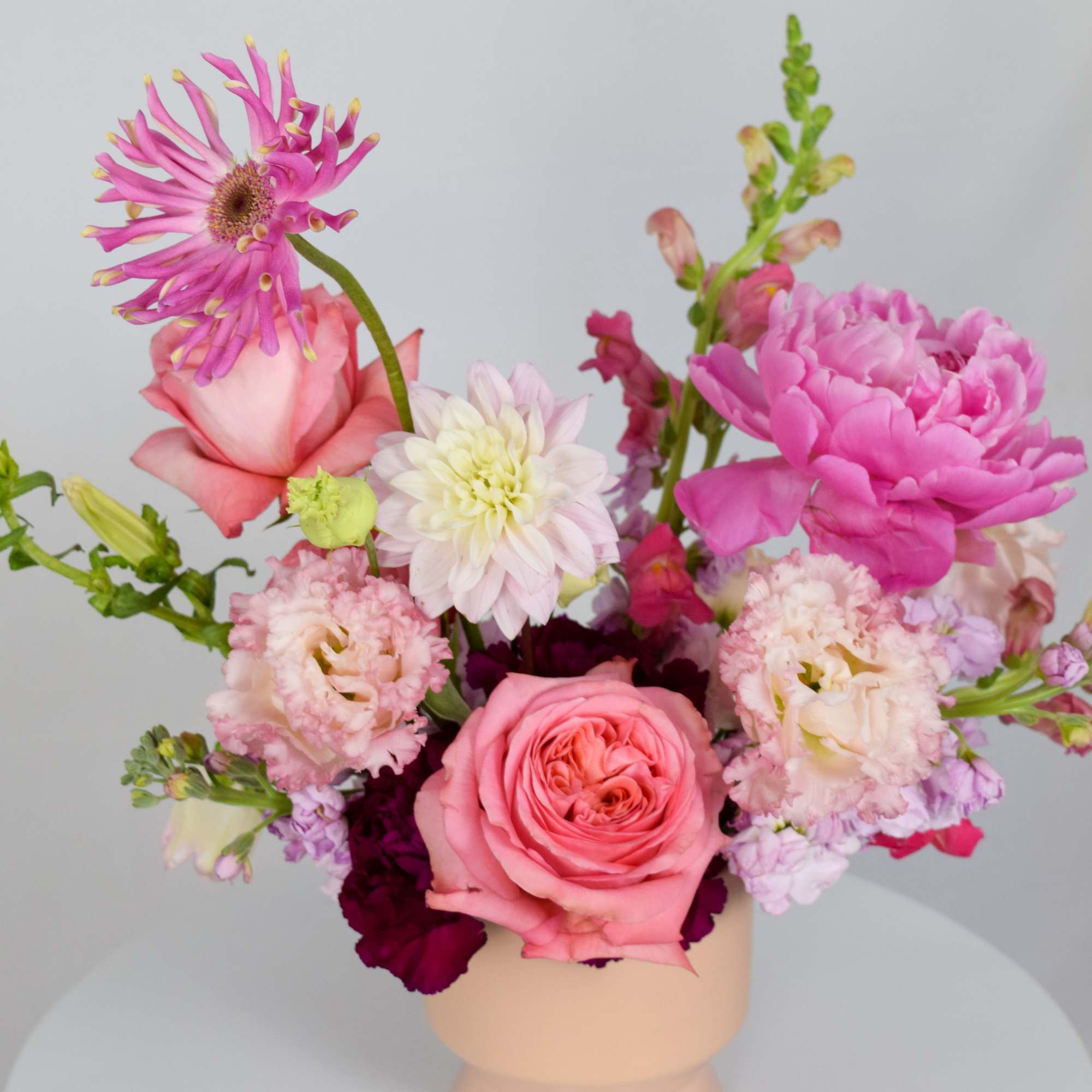 Pink and white mixed flower arrangement in a beige vase
