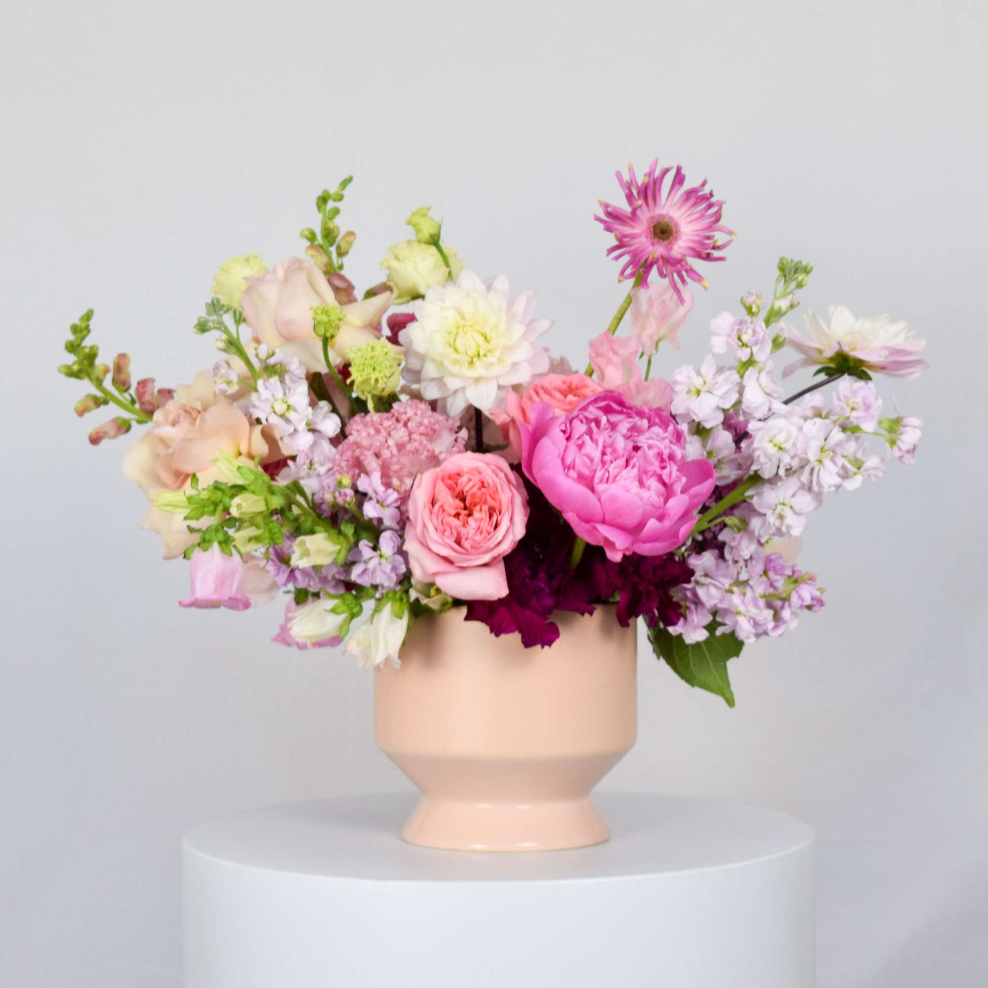 Pink and white mixed flower arrangement in a peach vase