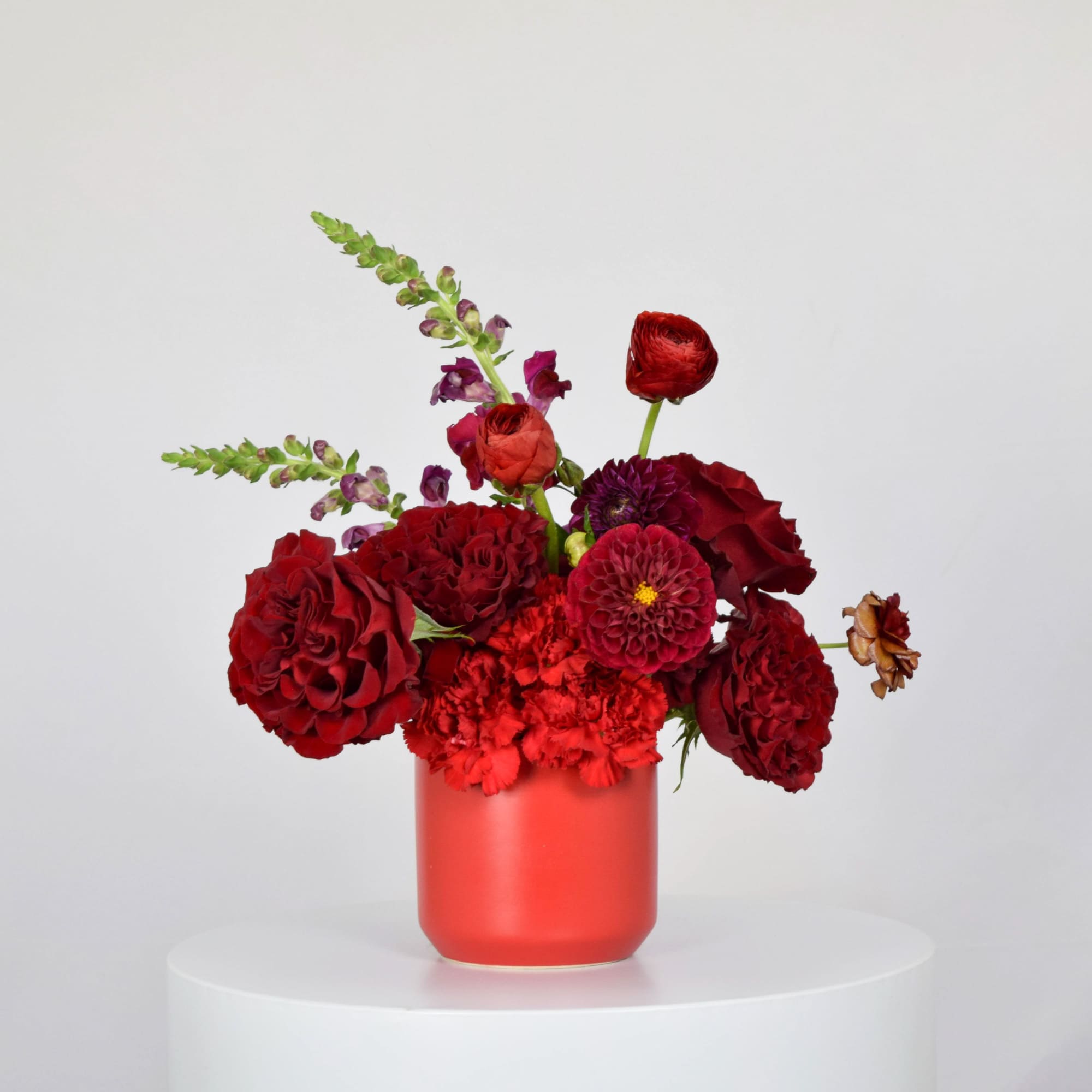 Red floral arrangement in a coral vase with mixed blooms