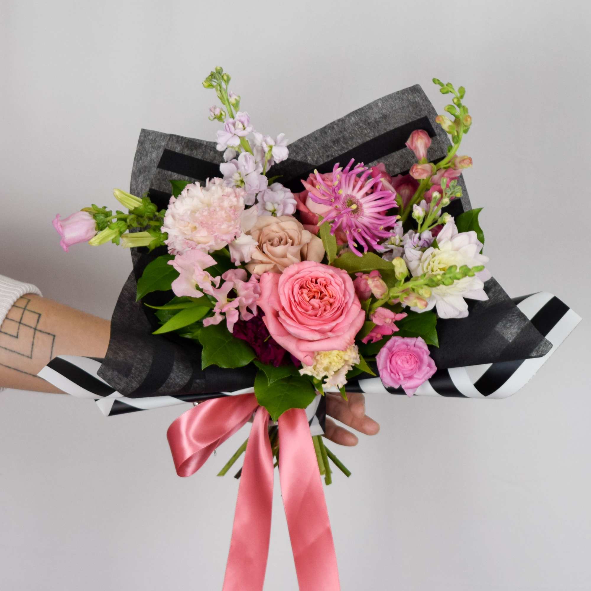 Hand-tied bouquet of pink and white flowers with a pink ribbon