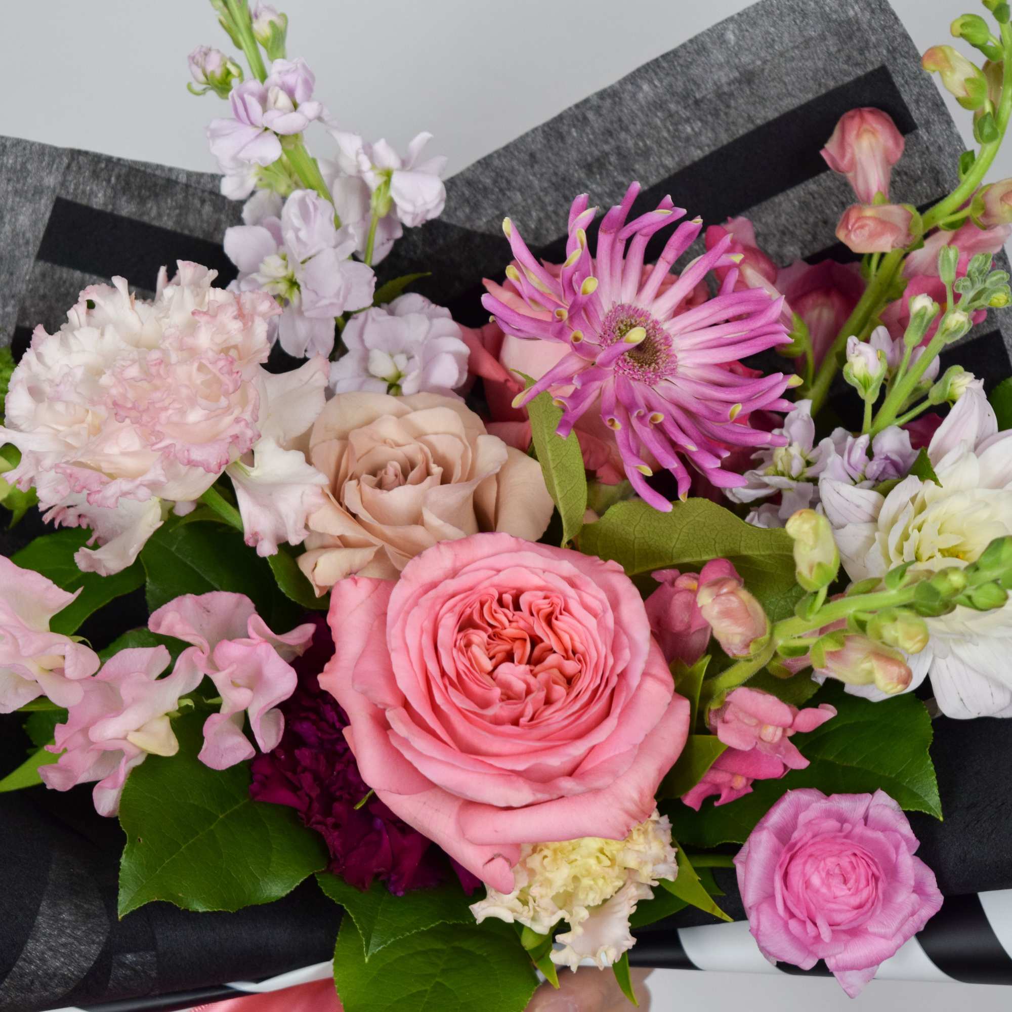 Pink and white mixed bouquet wrapped in black paper