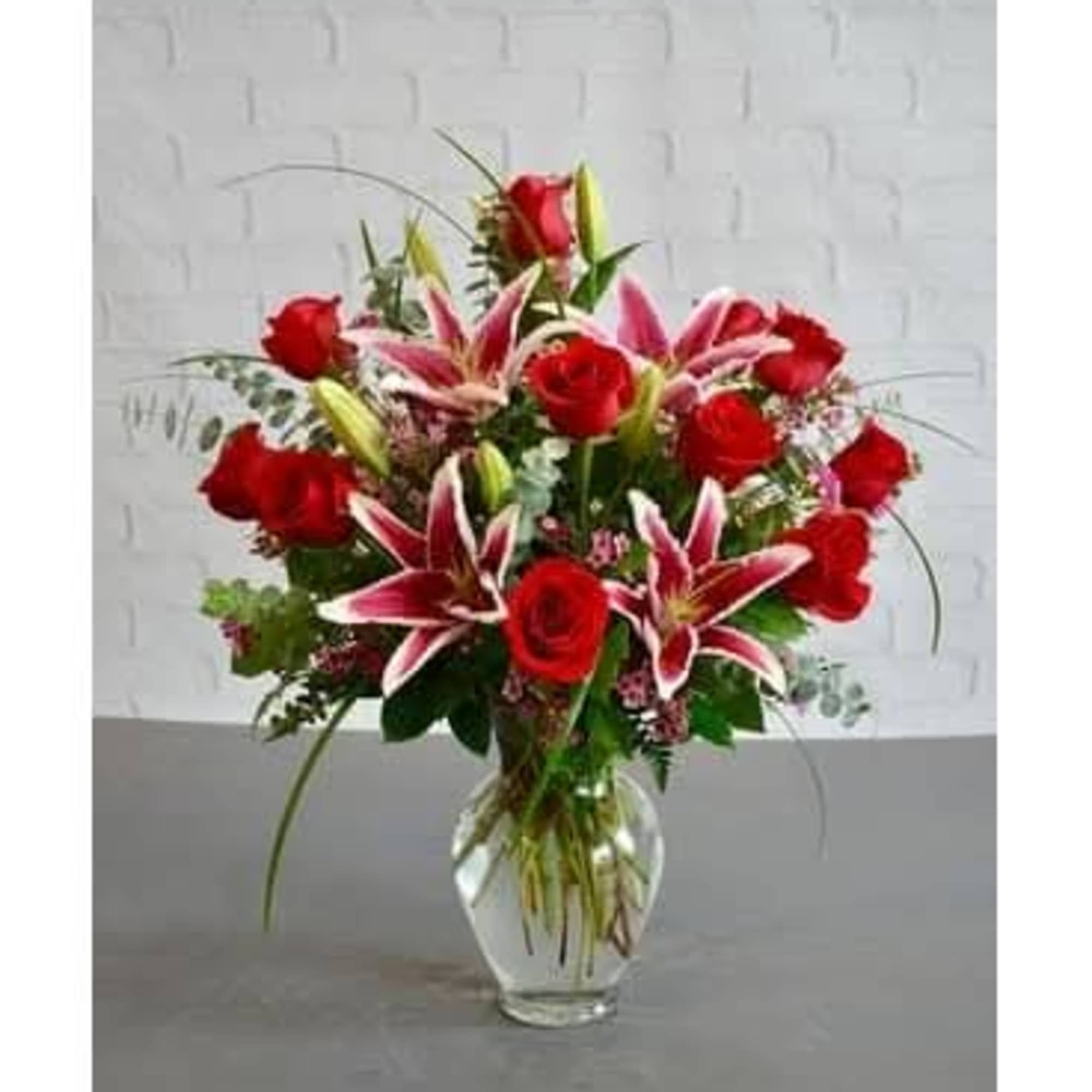 Red roses and pink lilies in a clear glass vase