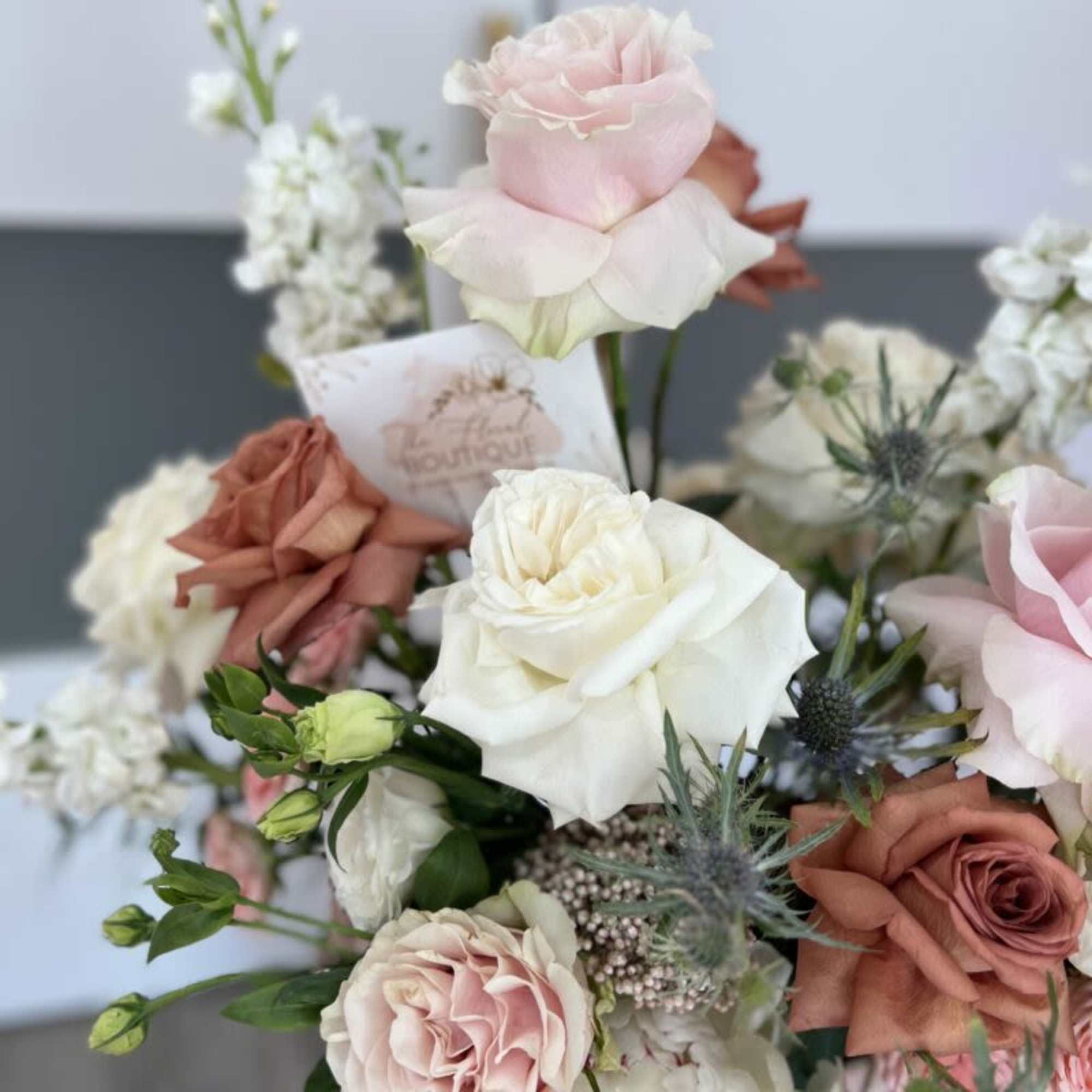 Bouquet of pink and white roses with spiky blue thistle flowers