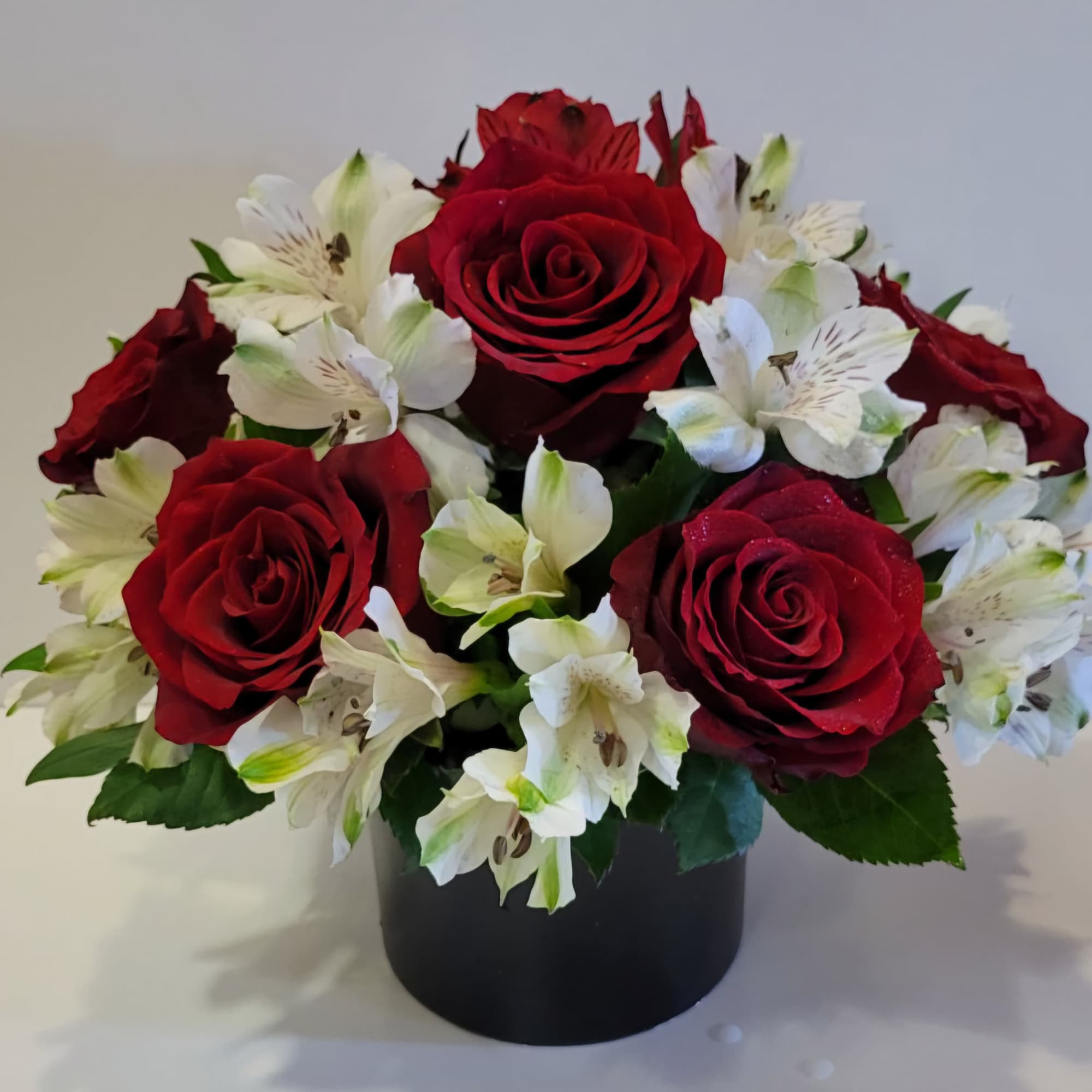 Red roses and white alstroemeria in a black container