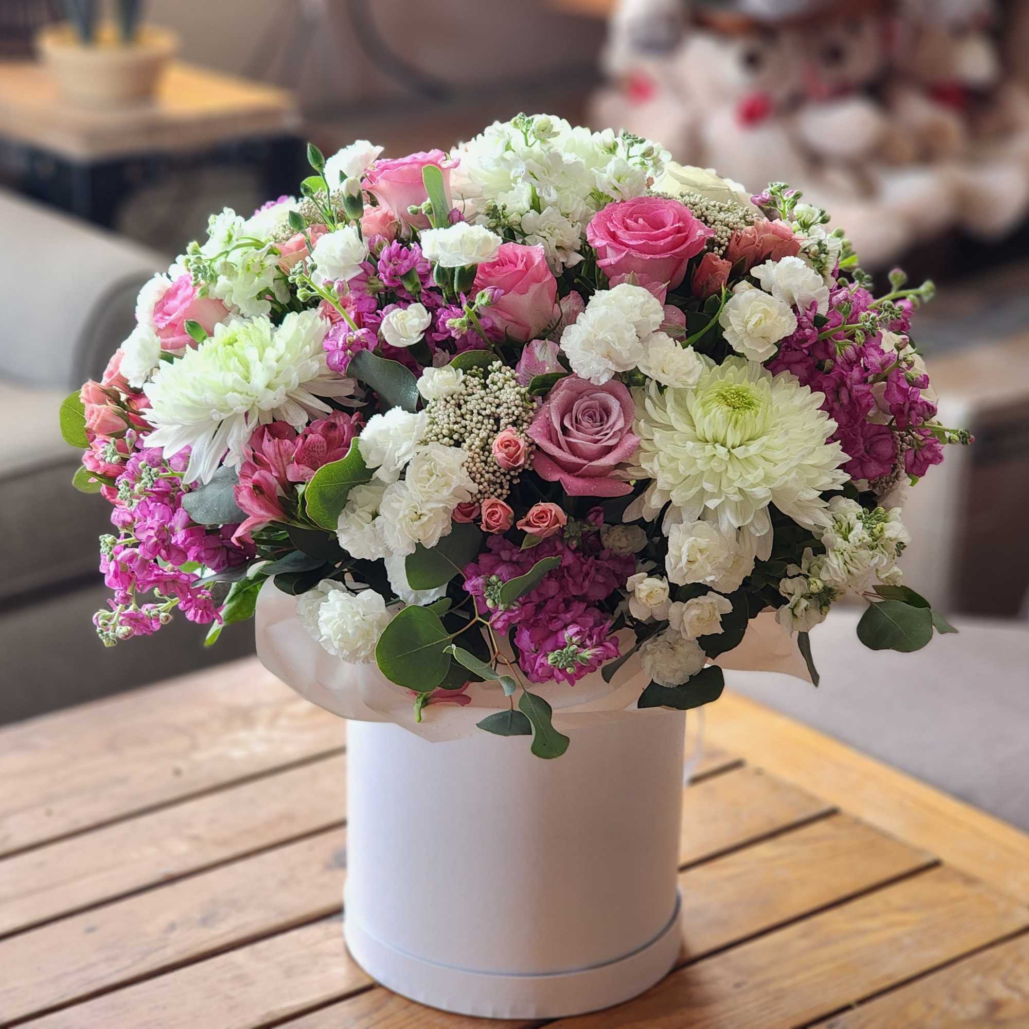 Pink and white mixed flower arrangement in a white hatbox
