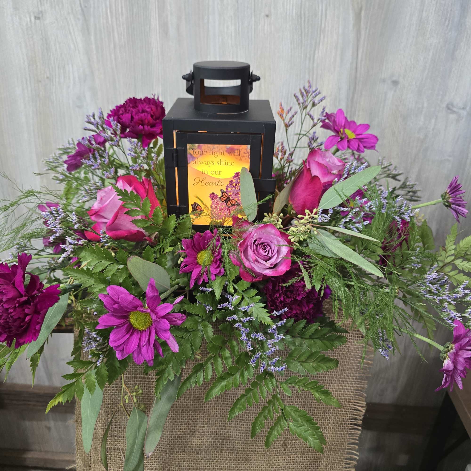 A beautiful lantern sympathy arrangement with a ray of purple tone flowers.