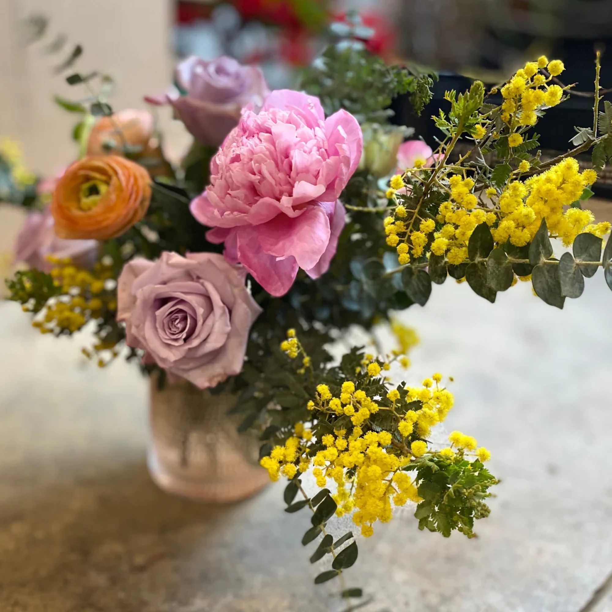 Bouquet with pink peony, lavender rose, and yellow mimosa in a vase