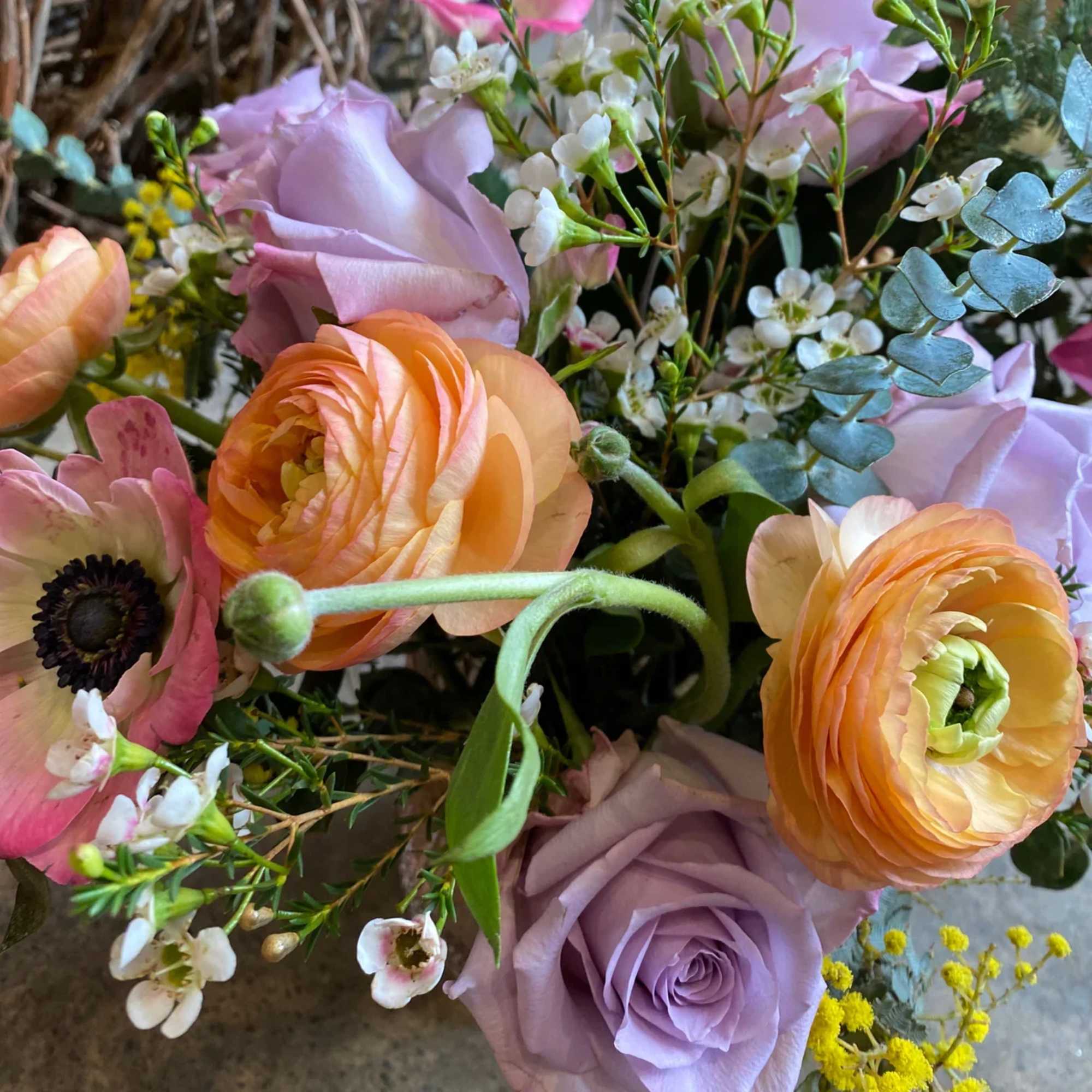 Bouquet of lavender roses, peach ranunculus, and pink anemones
