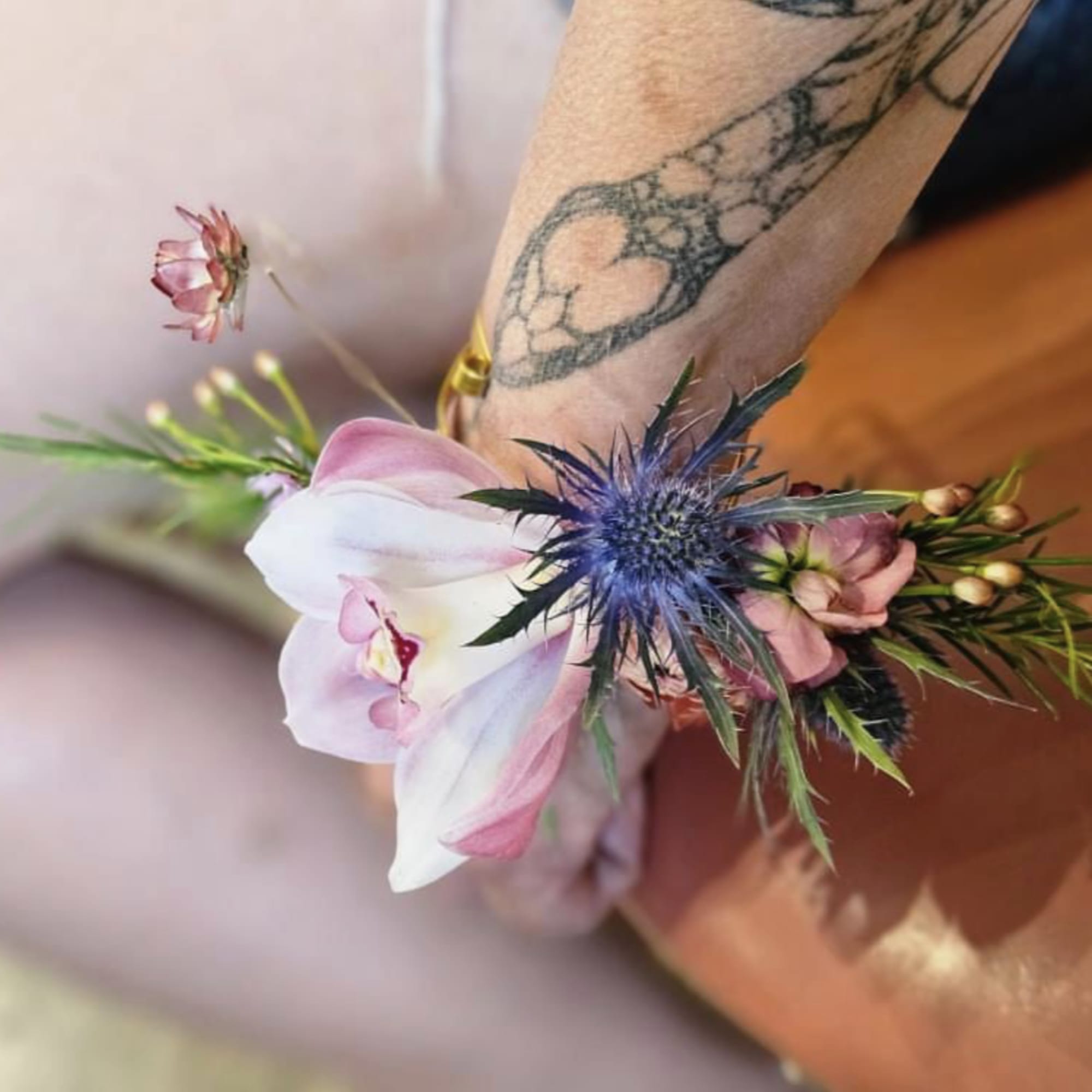 Small wrist corsage with pink and white flowers and a blue thistle bloom