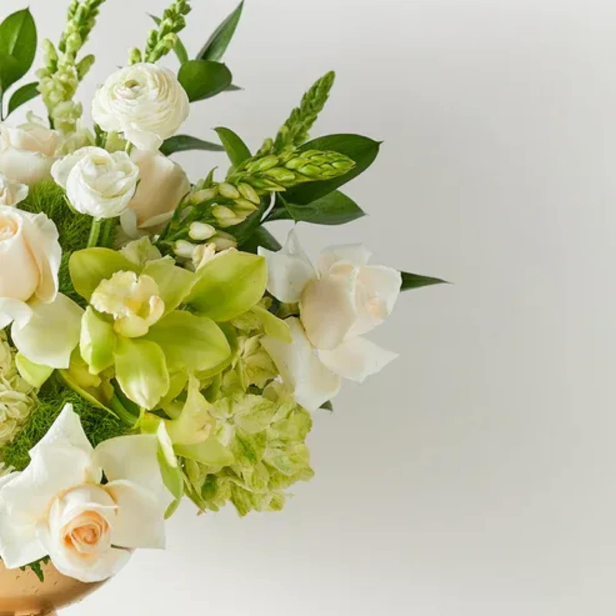White and pale green floral arrangement in a gold vase