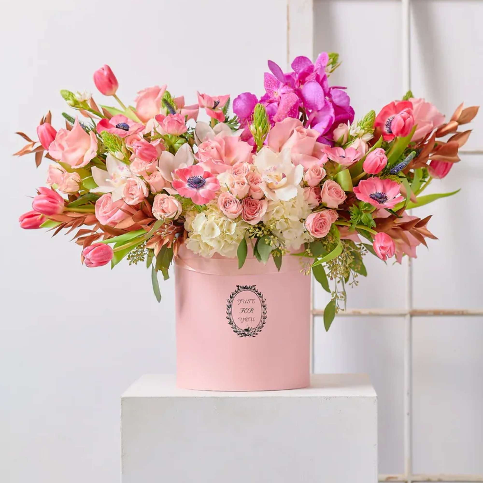 Pink and white mixed flower arrangement in a pink hat box
