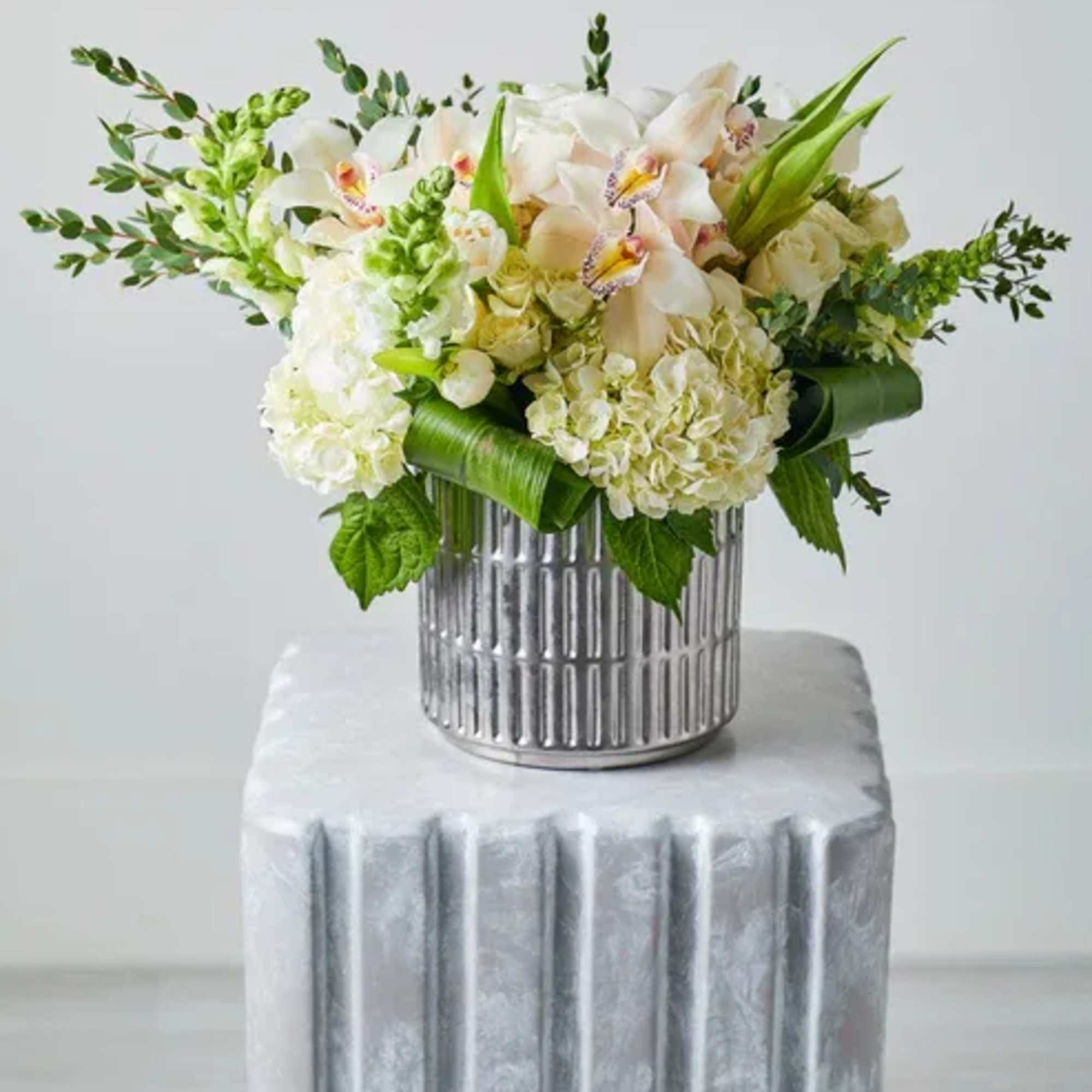 White and pale peach floral arrangement in a silver vase