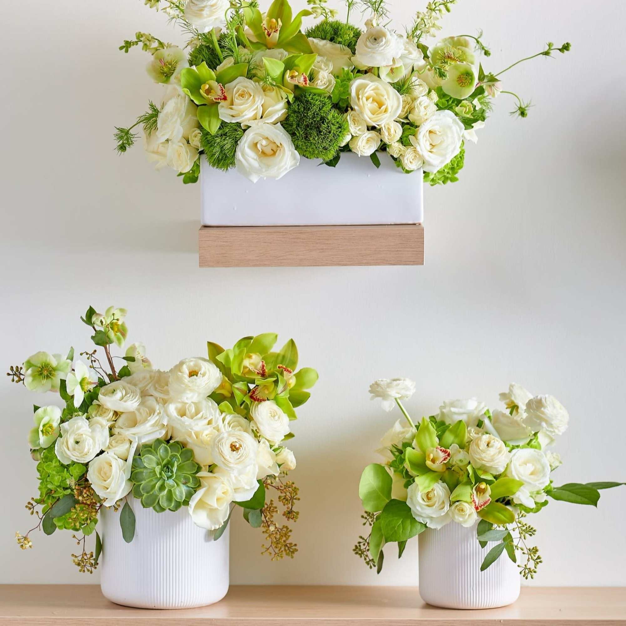White floral arrangements with green accents in white containers