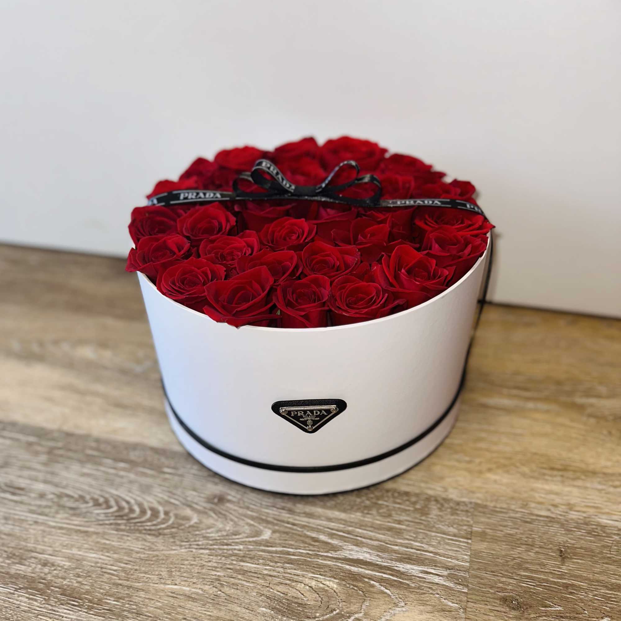 Round box filled with red roses and a black ribbon
